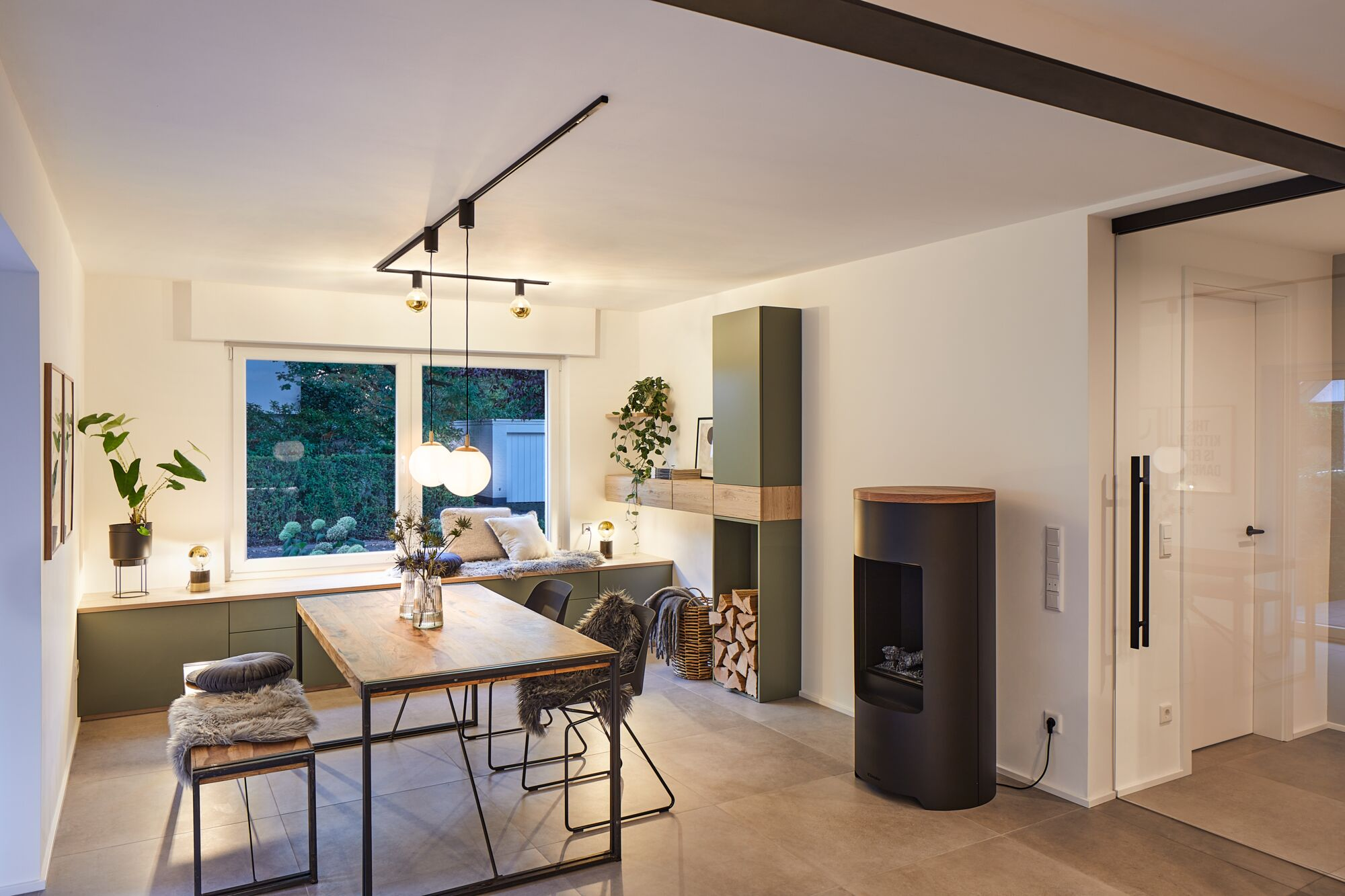 Modernes Esszimmer mit Holztisch, Kamin und Fenstersitzbank.