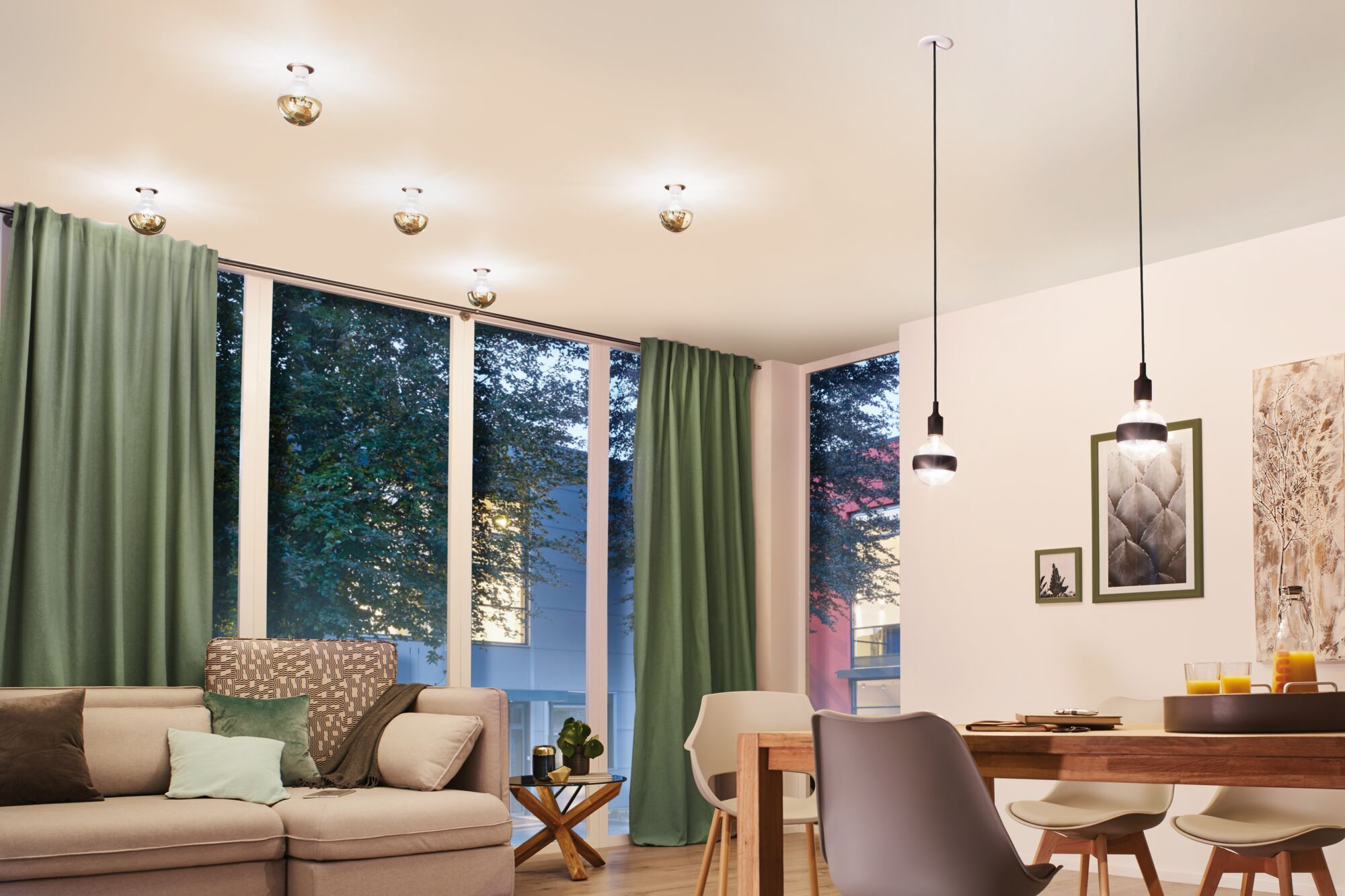 Ein Wohnzimmer mit Sofa, Tisch und Fenstern, durch die Bäume zu sehen sind.