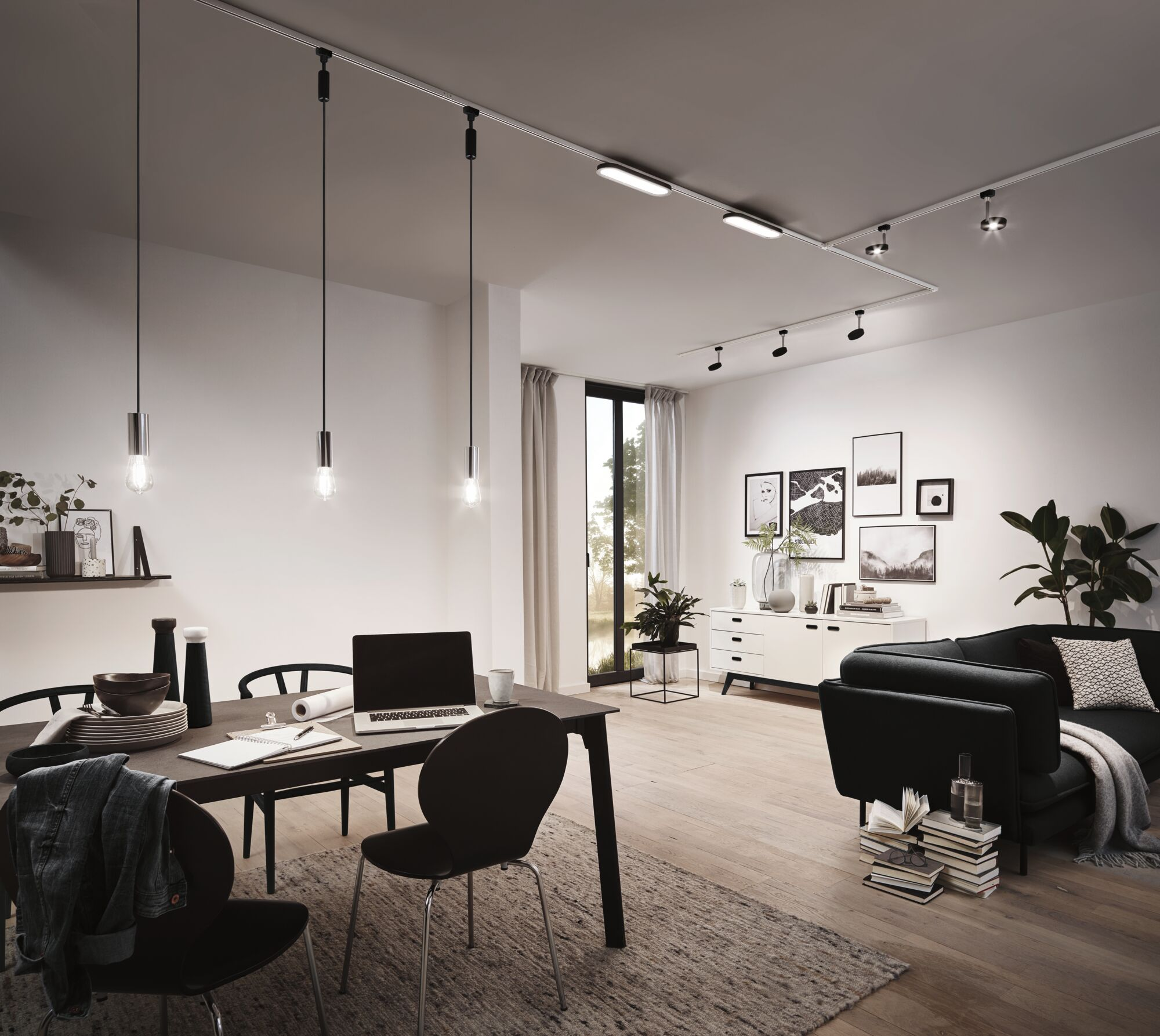 Ein moderner Ess- und Wohnbereich mit schwarzem Sofa, Esstisch und Laufschienenbeleuchtung.