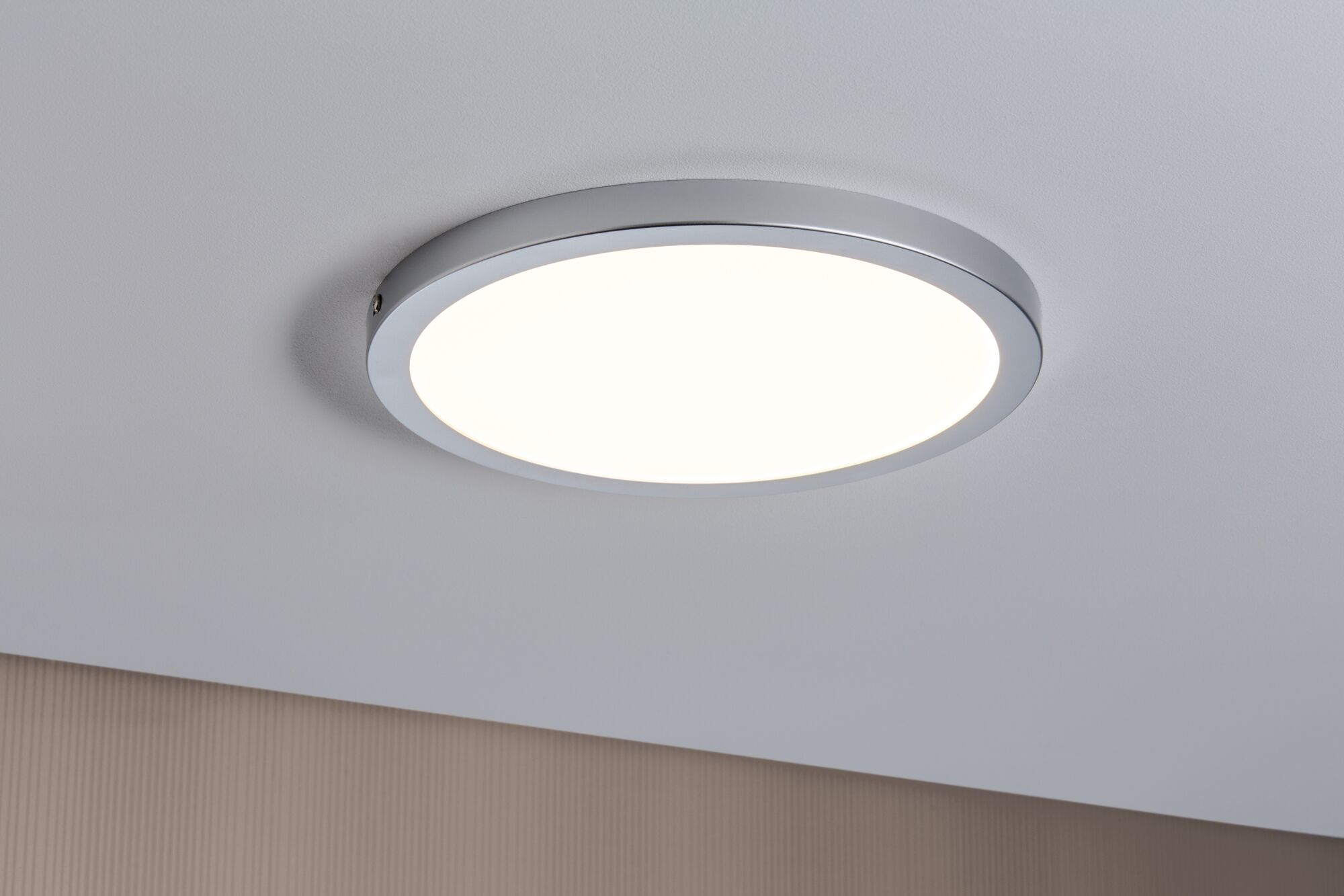 Una plafoniera rotonda con bordo cromato su soffitto bianco.