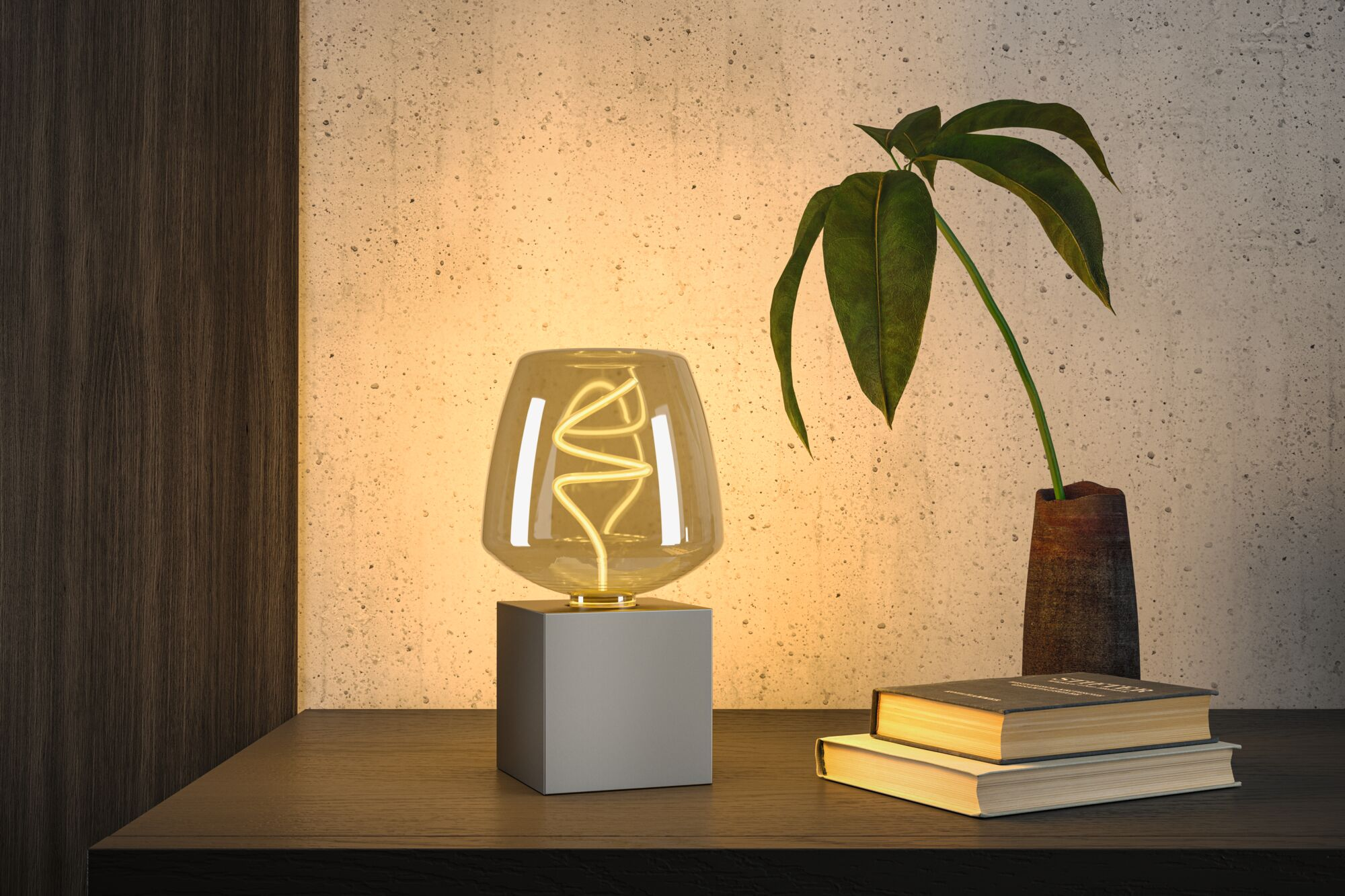 Lampa stołowa z szarą podstawą w kształcie sześcianu i bursztynowym kloszem.