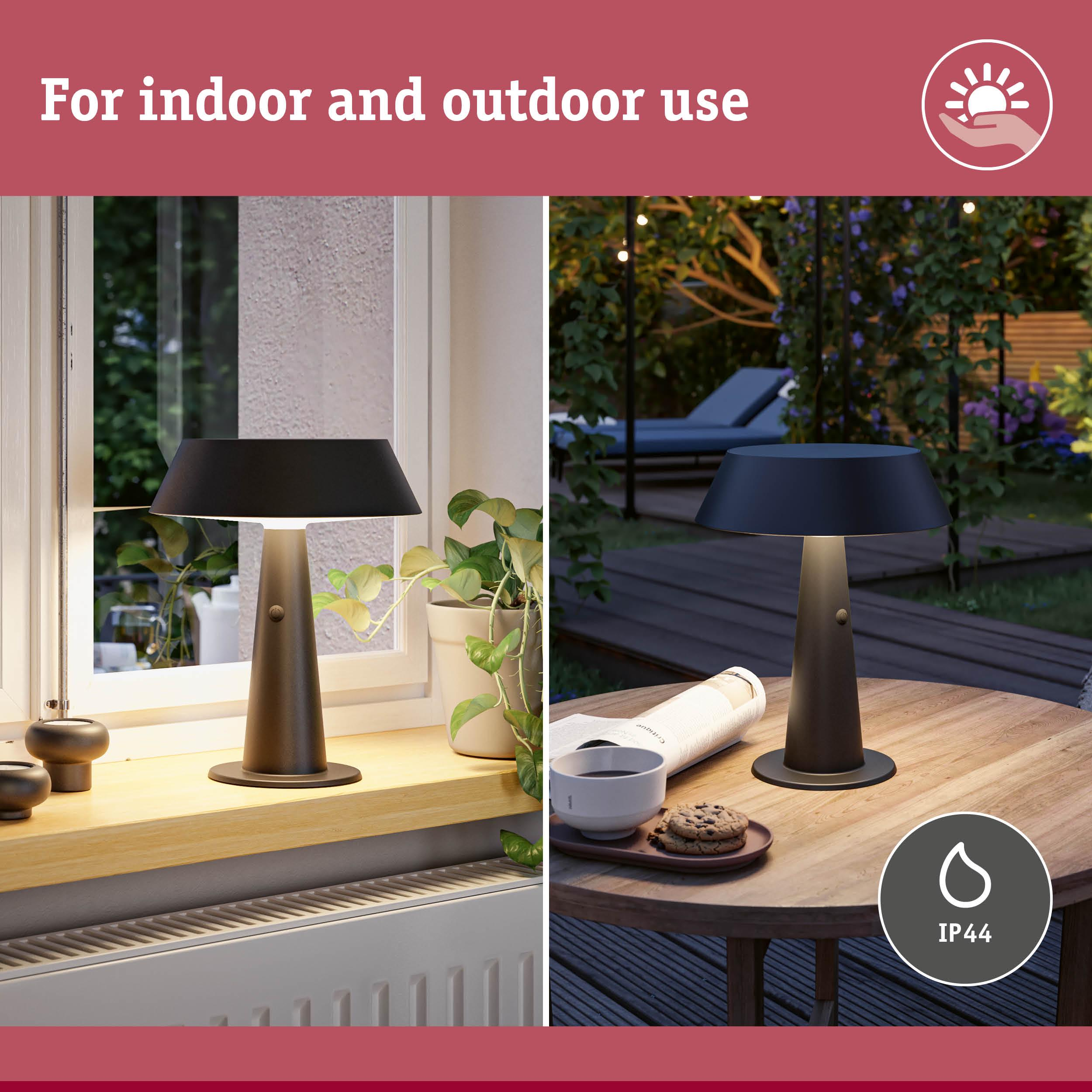 Nowoczesna lampa wewnątrz i na zewnątrz, na stole z kawą, ciasteczkami i książką.