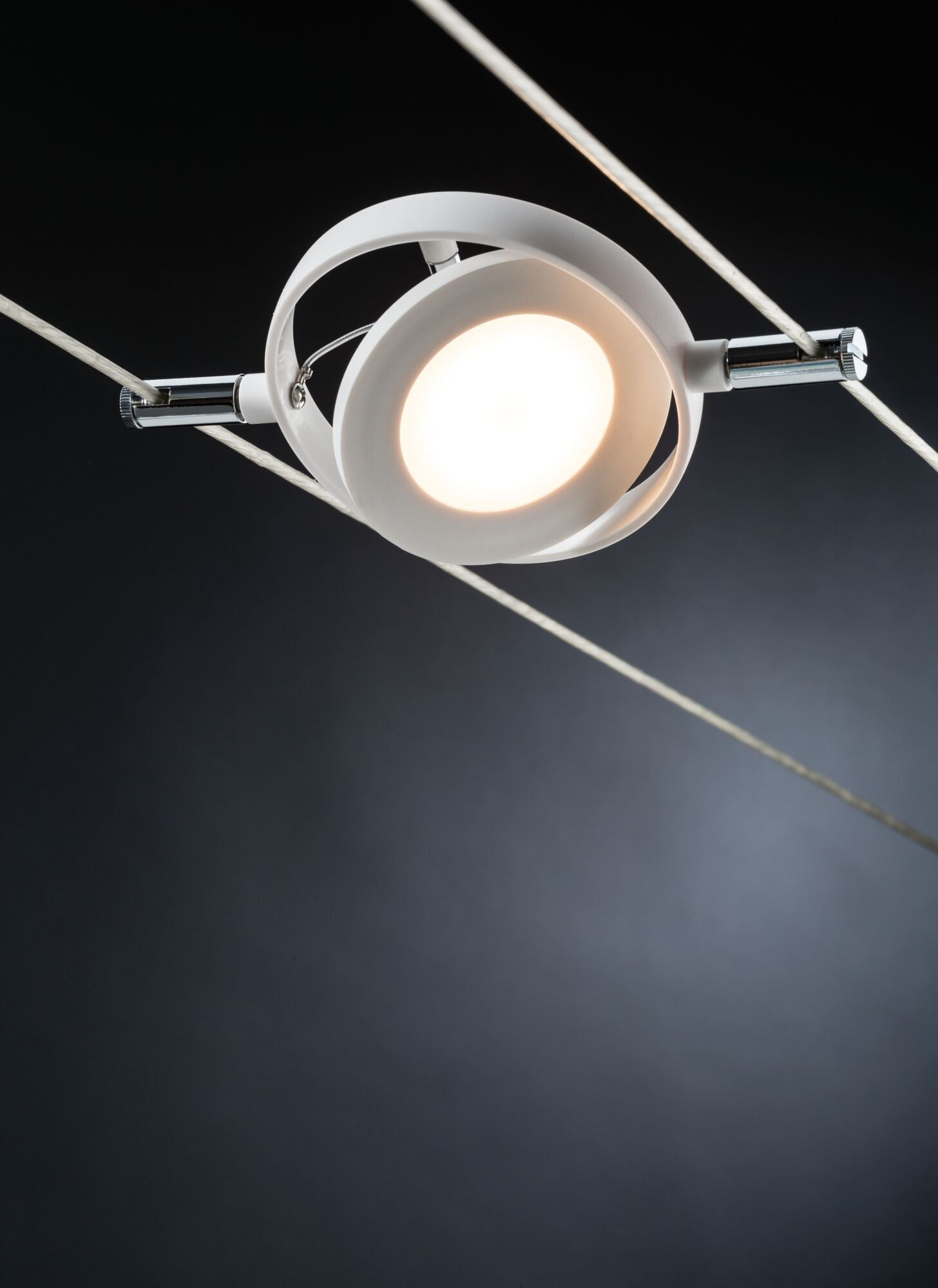 Una lampada da soffitto bianca e moderna dal design circolare, illuminata dall'interno, sospesa con fili sottili.