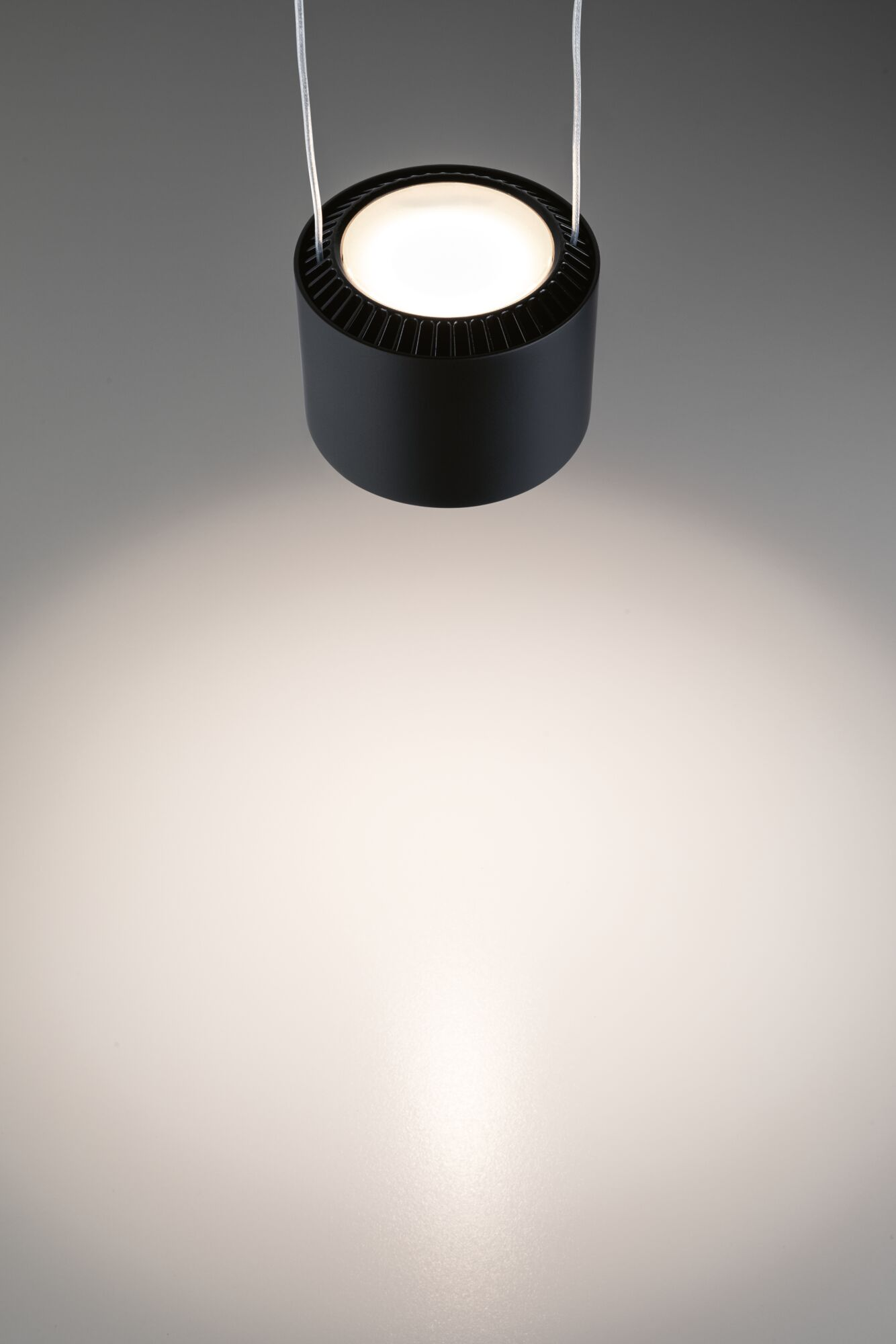 Eine schwarze Hängeleuchte mit hellem Licht, das nach unten scheint.