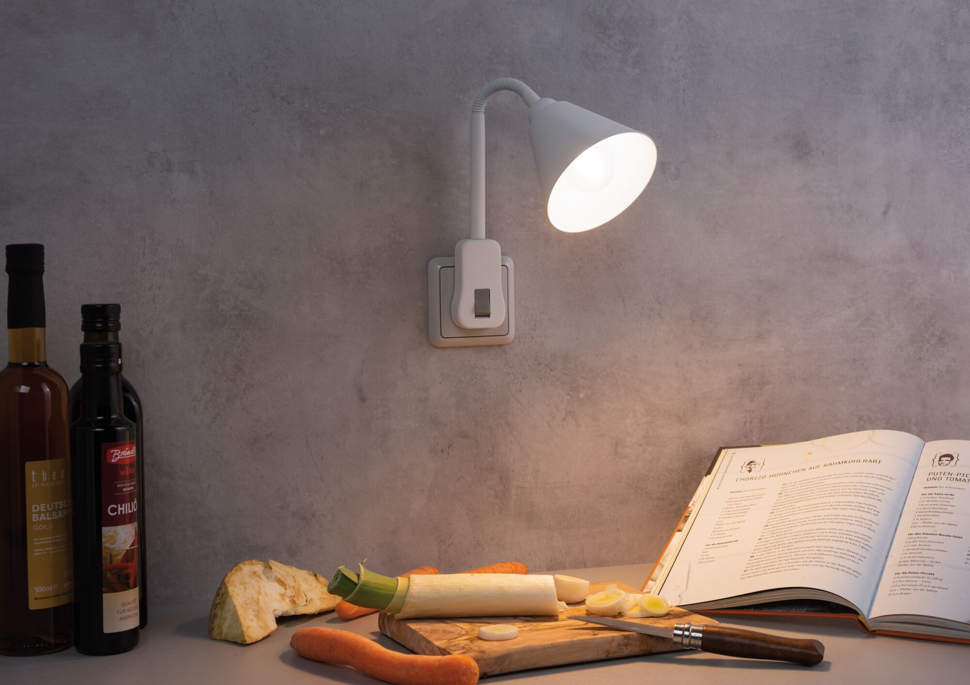 Una lampada illumina un piano di lavoro con ingredienti da cucina e un libro di ricette.