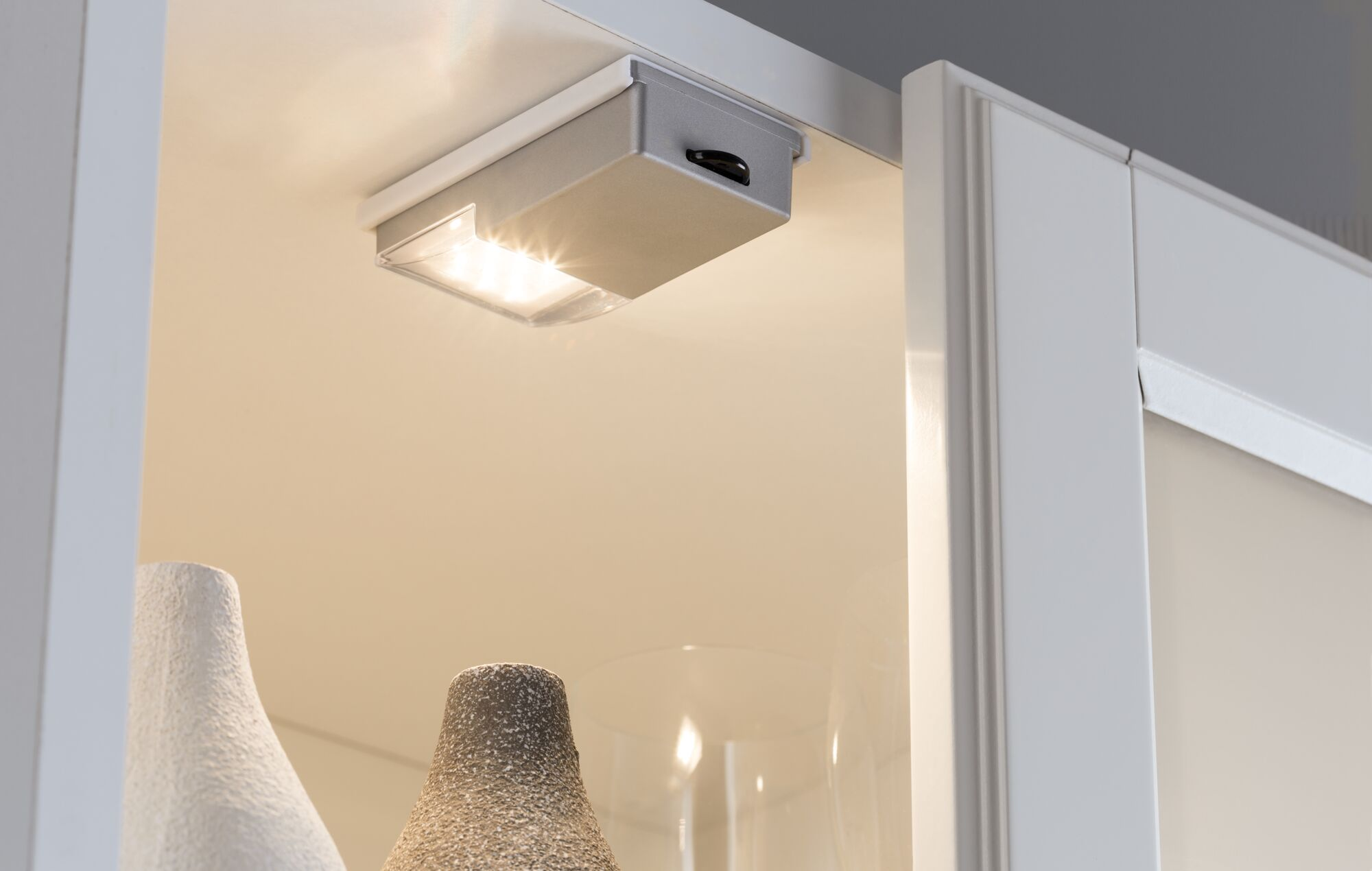 Ein kleiner silberner Schrankaufbau mit Licht über zwei Vasen.