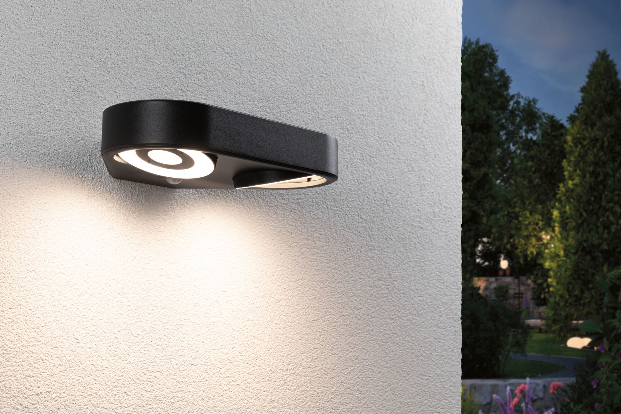 Schwarze Wandleuchte mit kreisförmigem Licht, leuchtet auf einer weißen Wand.
