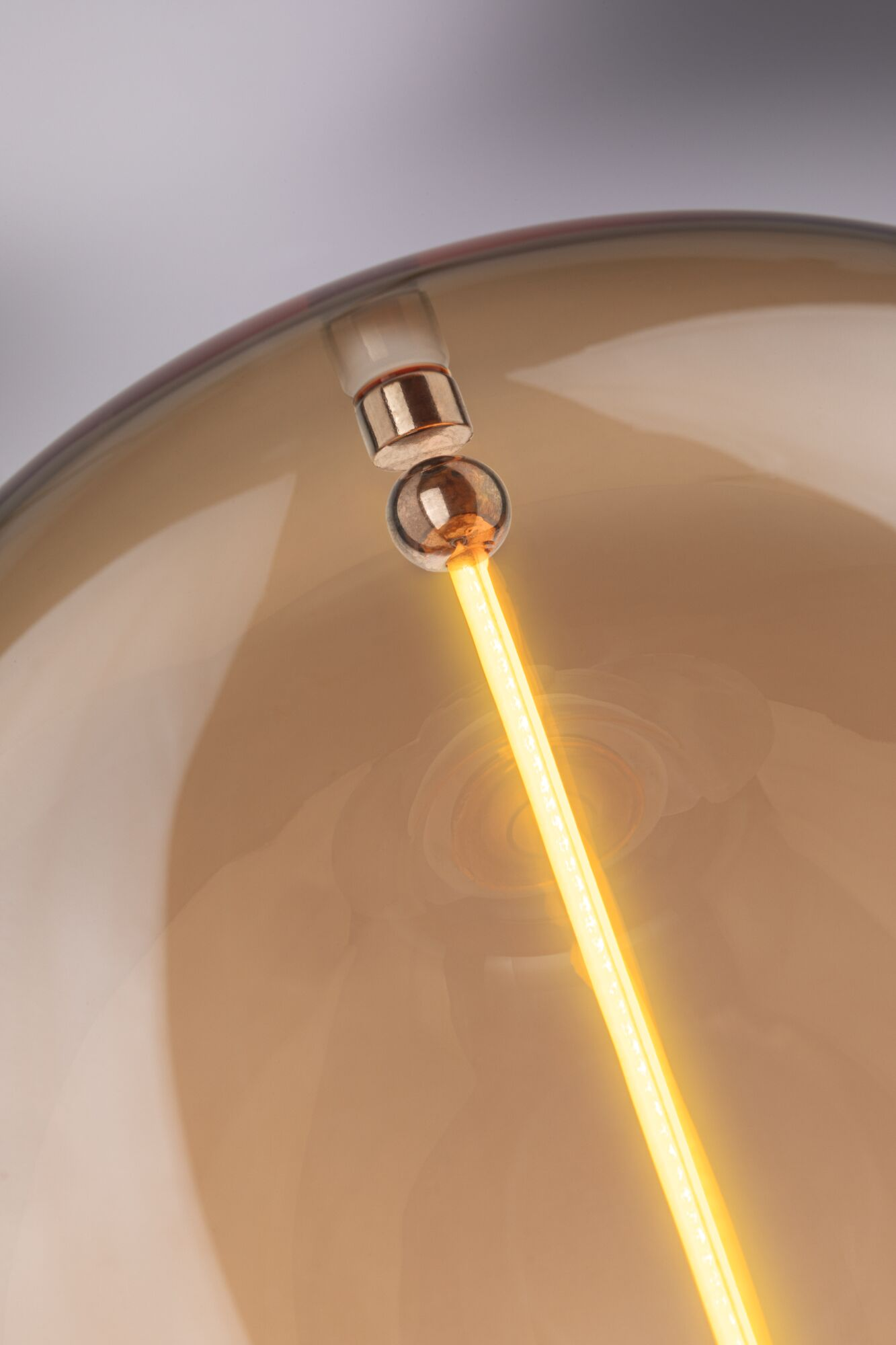 Jasny świetlny pręt wyłania się z brązowej szklanej kuli.