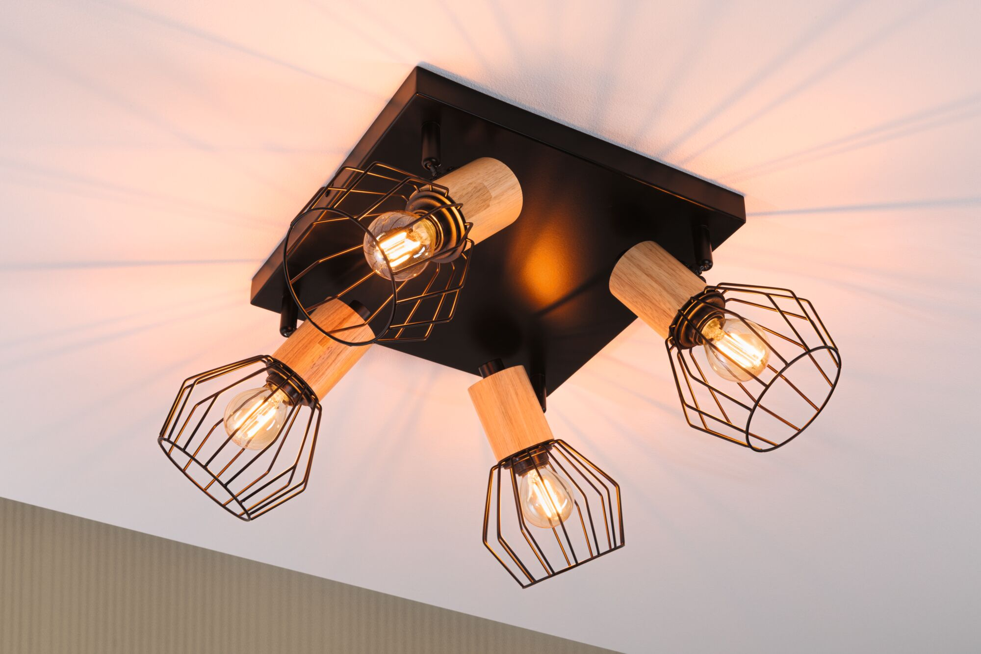 Schwarzer Deckenstrahler mit vier Lampen, Holzdetails und Drahtkörben.