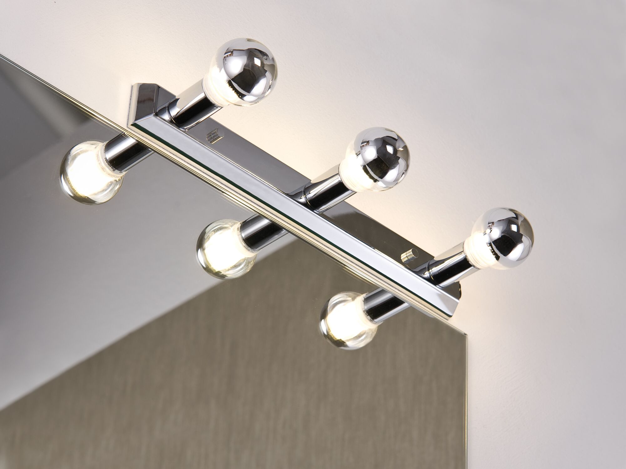 Ein moderner Wandspiegel mit vier Lichtern und Chromdetails.