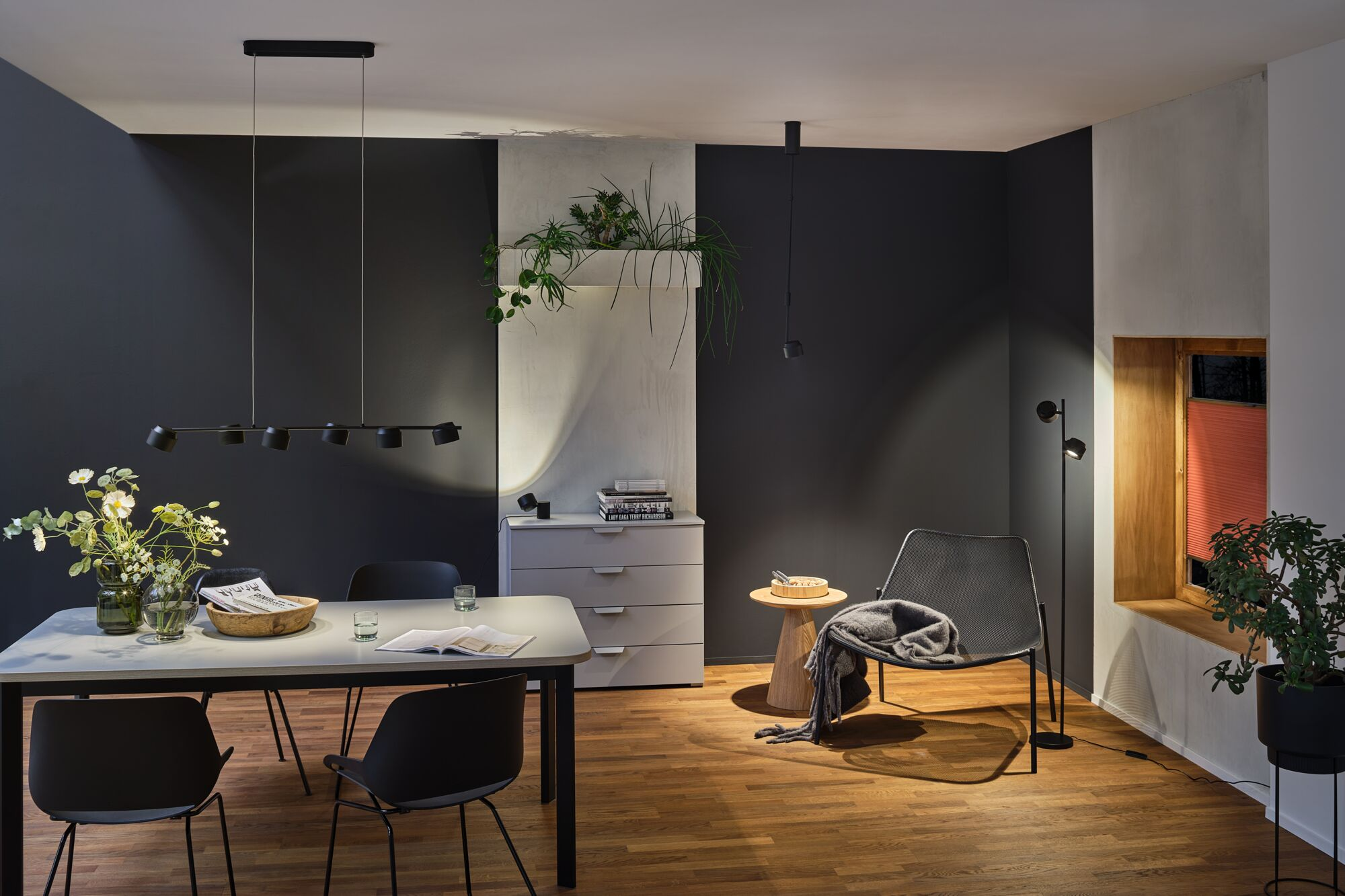 Ein Esszimmer mit modernem Tisch, Stühlen, Lampe und Dekoration.