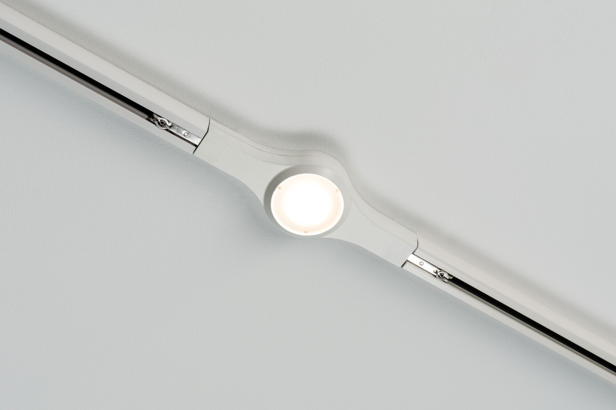 Eine weiße Deckenleuchte mit einem hellen Lichtpunkt auf einer weißen Decke.