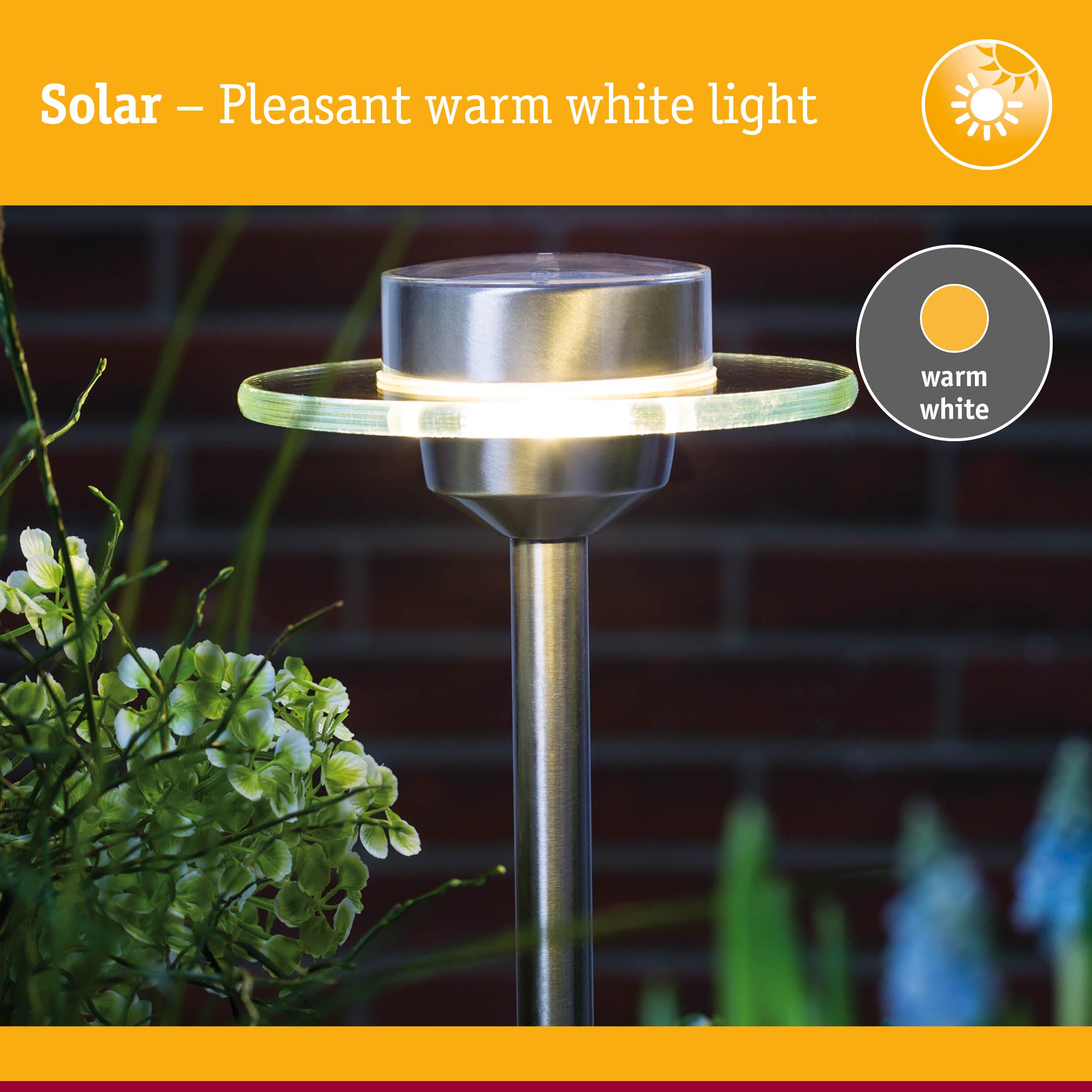 Lampe solaire à lumière blanc chaud, verre et métal, contre mur de briques.