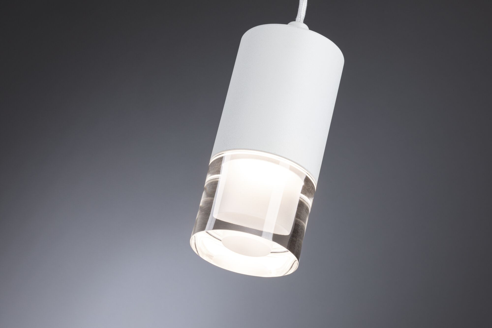 Eine weiße Zylinderlampe mit klarem Glasdetail leuchtet auf grauem Hintergrund.