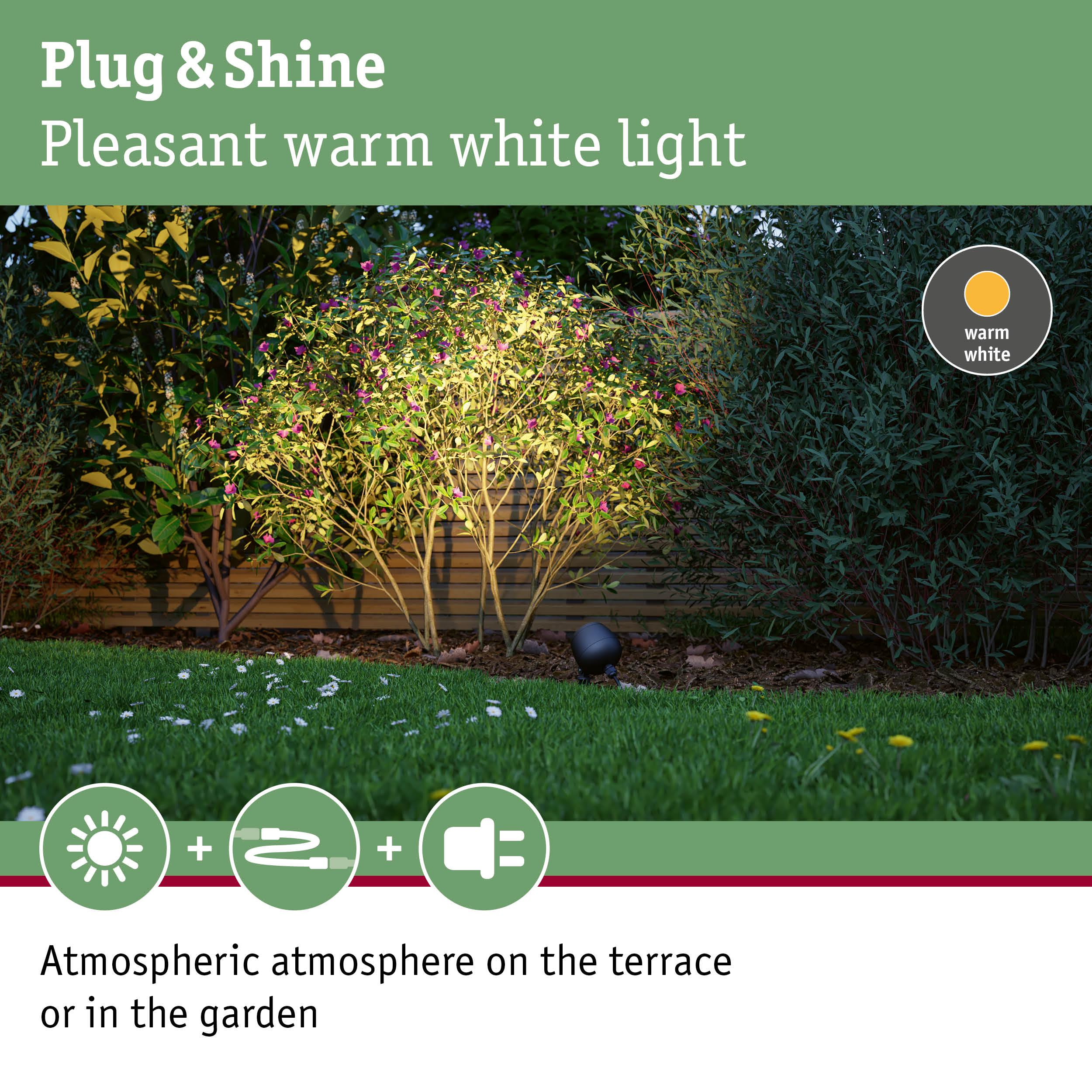 Gartenbeleuchtung mit warmweißem Licht auf einem Rasen mit Blumen.