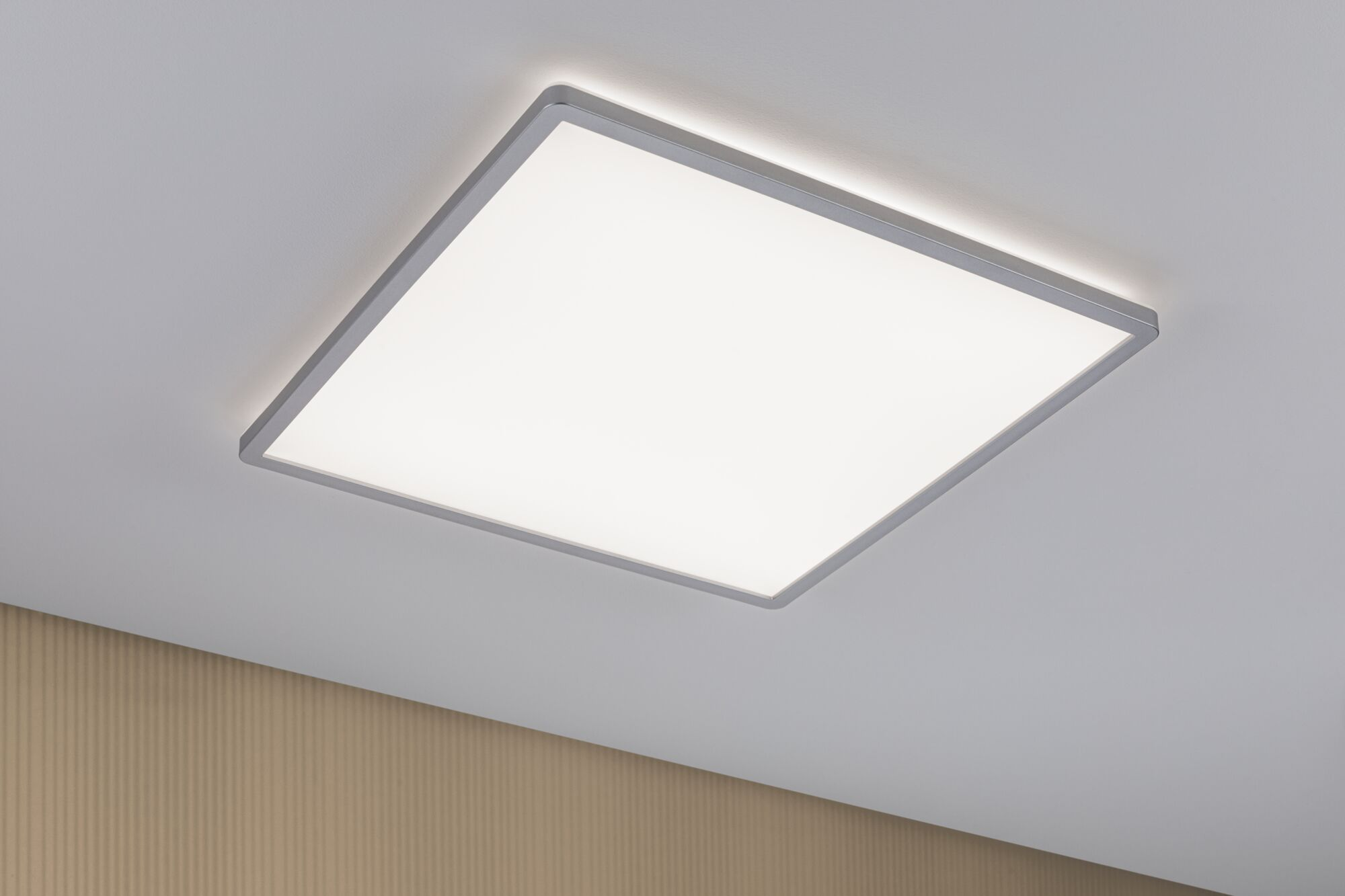 Ein quadratisches Deckenlicht mit grauem Rahmen leuchtet hell.