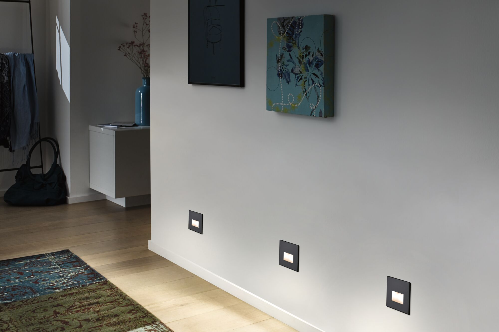 Korytarz z kinkietami, sztuką na ścianie i dywanem.