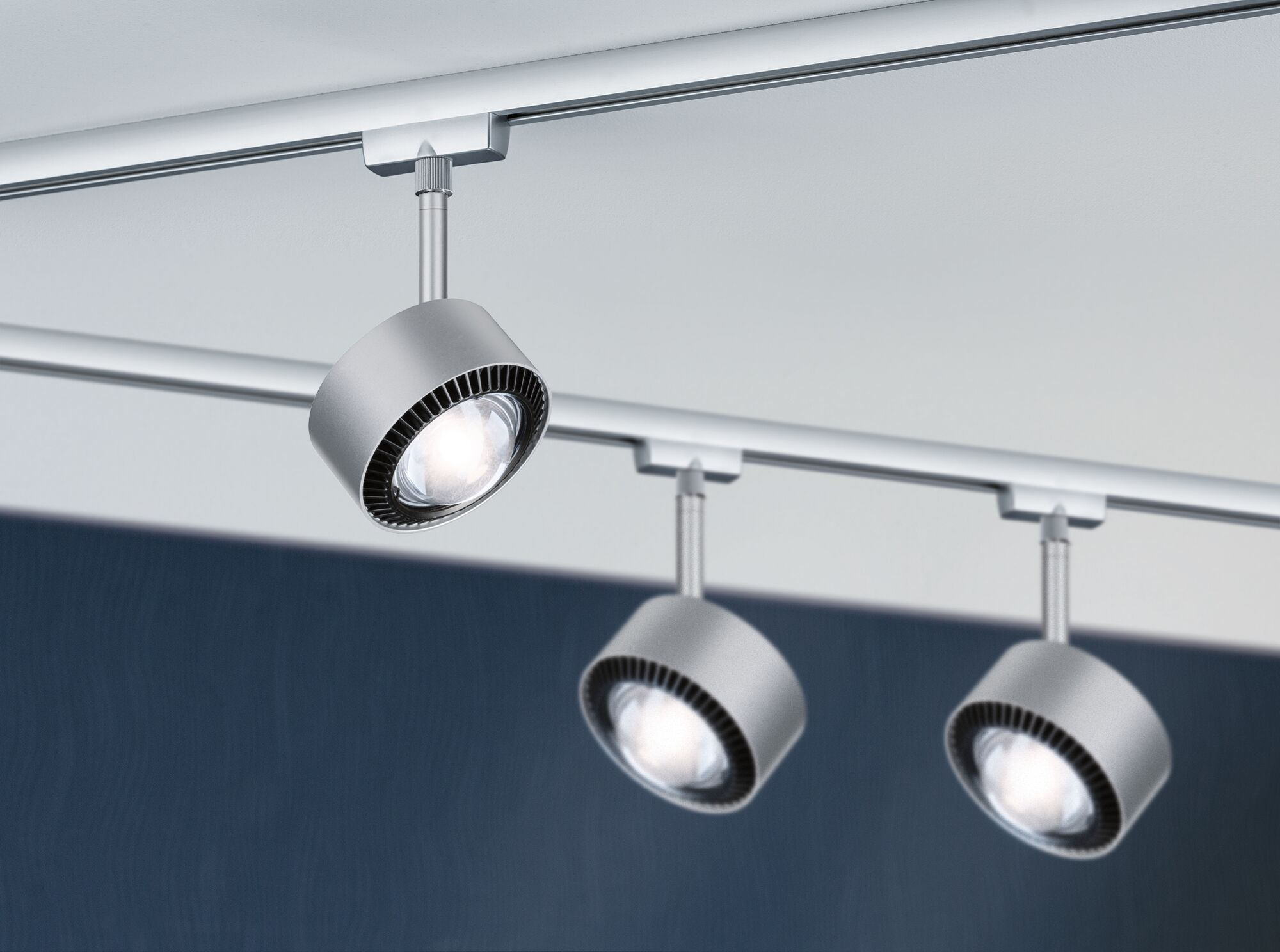 Drei silberne Schienenstrahler mit LED-Licht sind an einer Deckenleiste montiert.