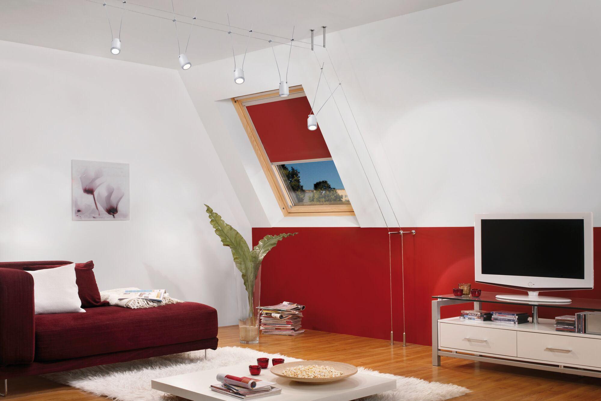 Modernes Wohnzimmer mit rotem Sofa, Fernseher und Dachfenster.