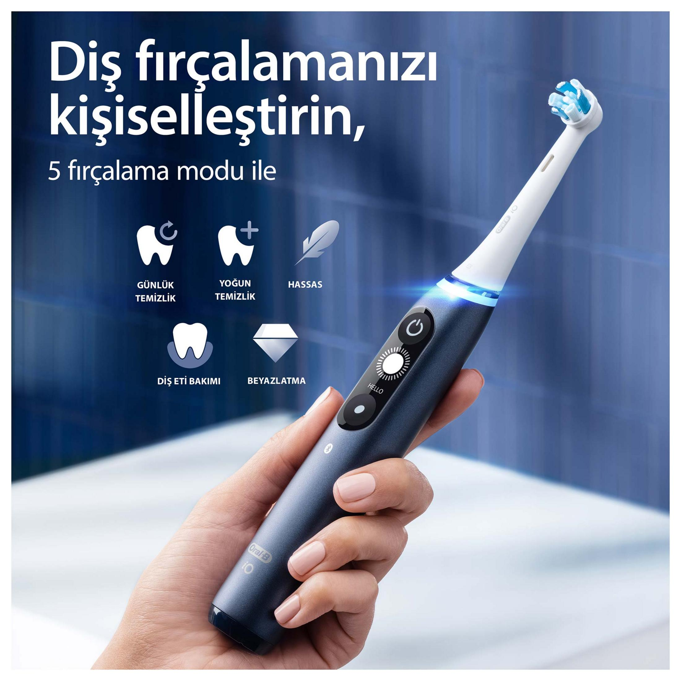 Una mano tiene uno spazzolino elettrico scuro con accenti blu.