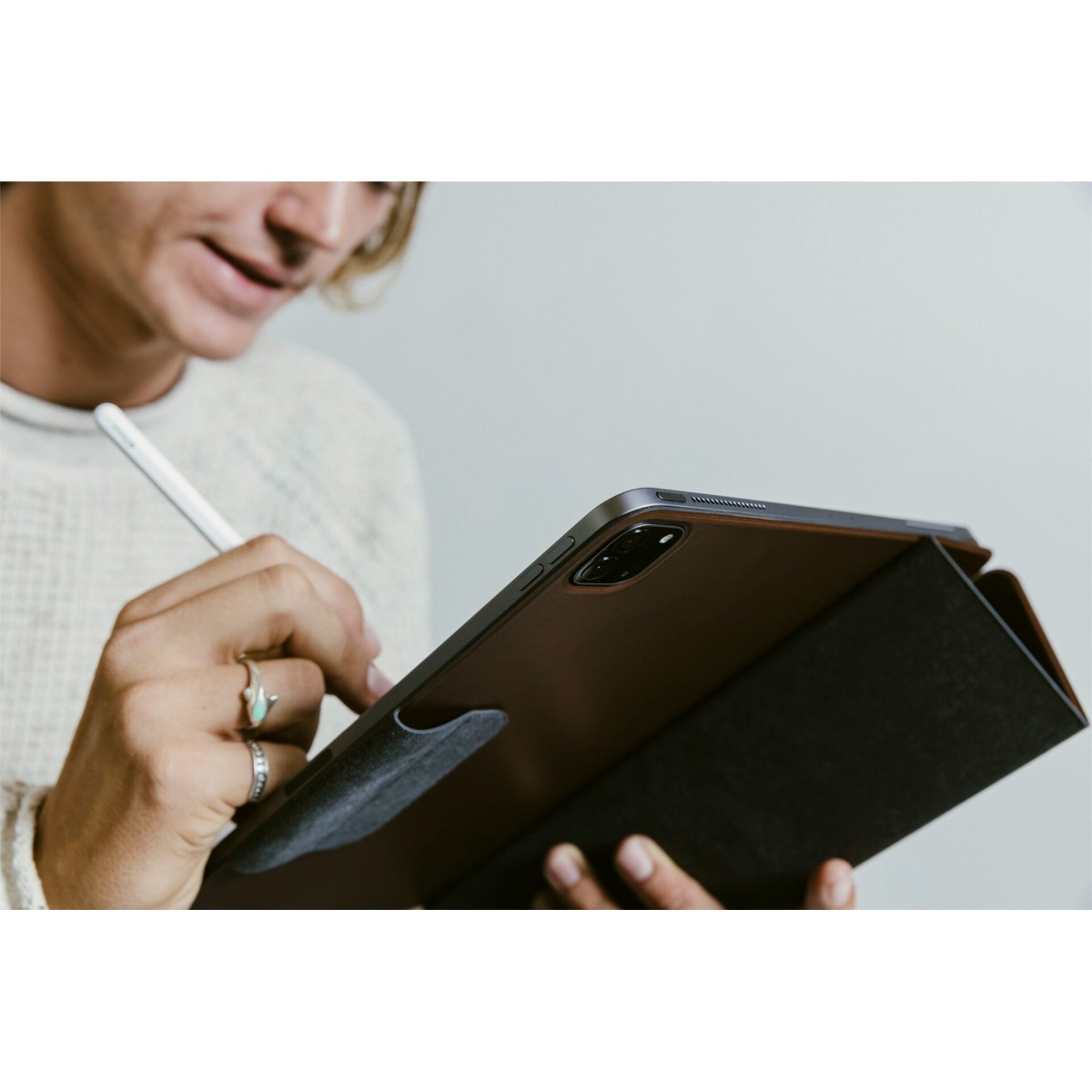 Person mit Stift schreibt auf braunem Tablet mit dunklem Bezug.