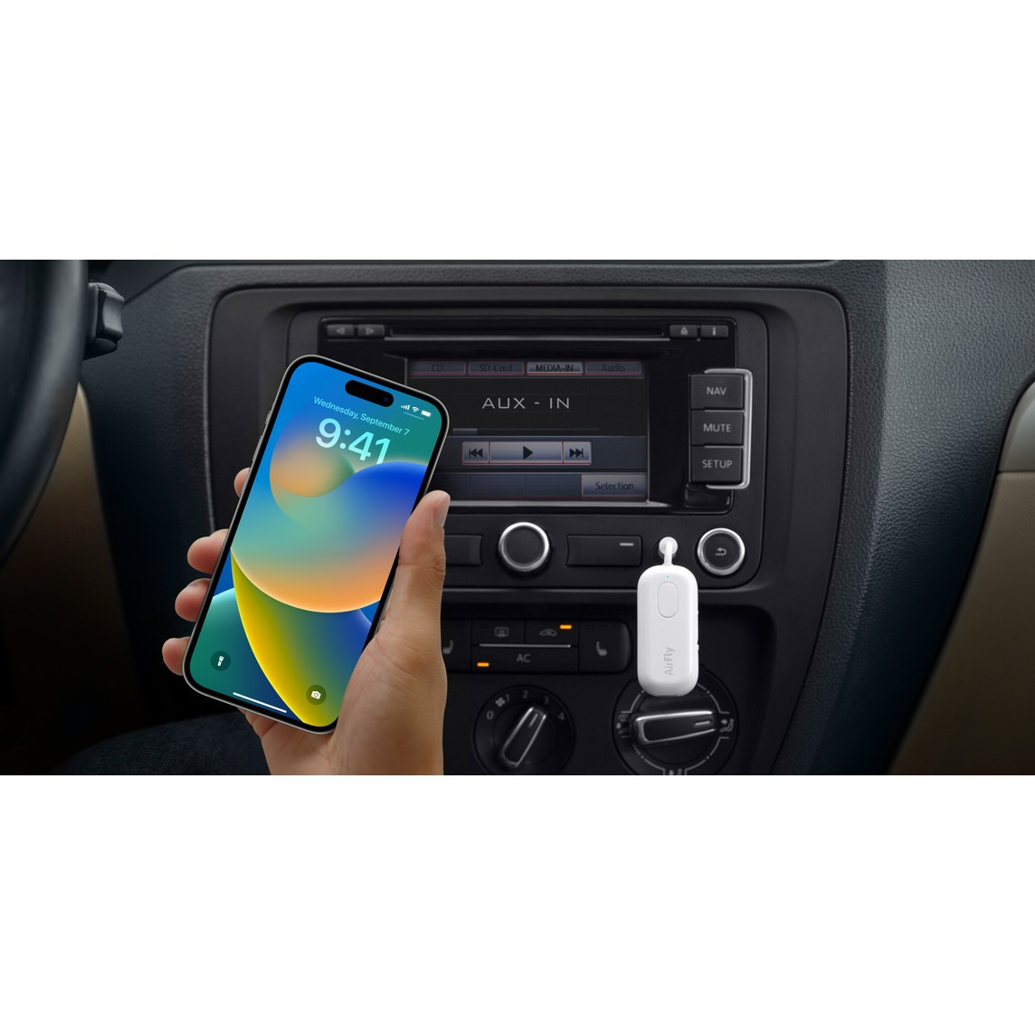 Ein iPhone wird vor einem Autoradio gehalten, das AUX-IN anzeigt. Ein weißes AirFly-Gerät steckt in einer Buchse.