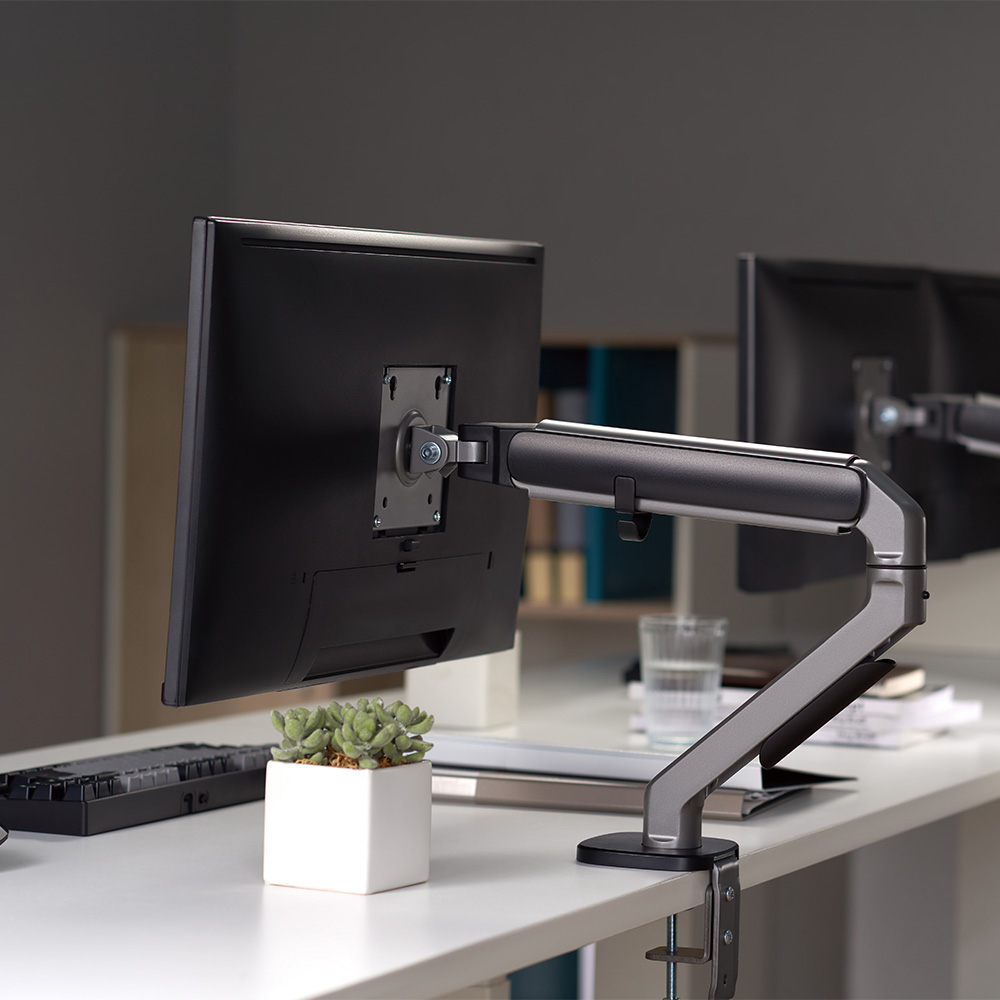 Ein Monitorarm hält einen schwarzen Bildschirm über einem weißen Topf mit Sukkulenten.