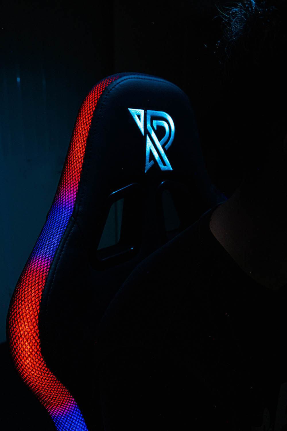 Ein schwarzer Gaming-Stuhl mit leuchtendem Logo und RGB-Beleuchtung.