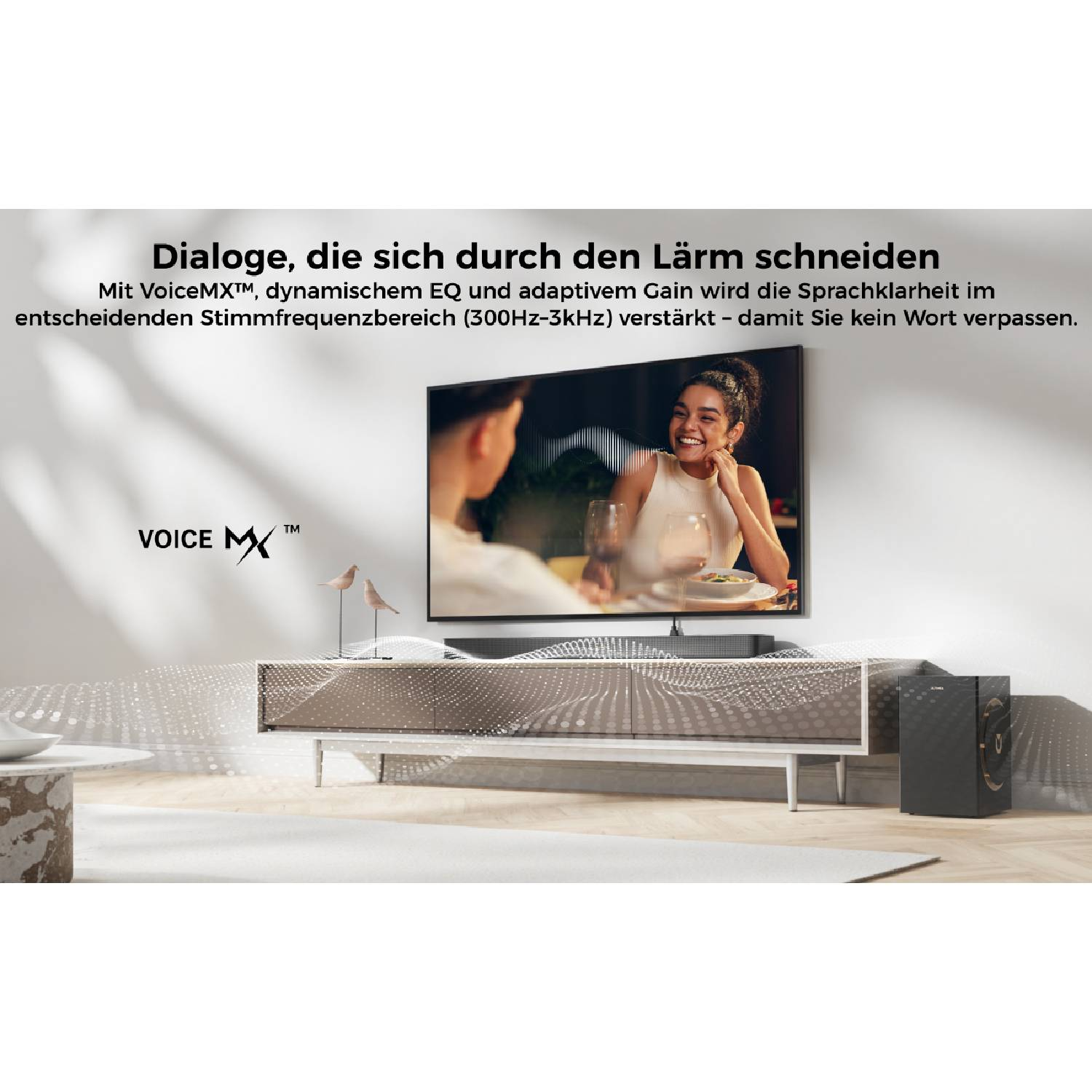 Une télévision montre un couple riant. Un subwoofer se trouve à côté.