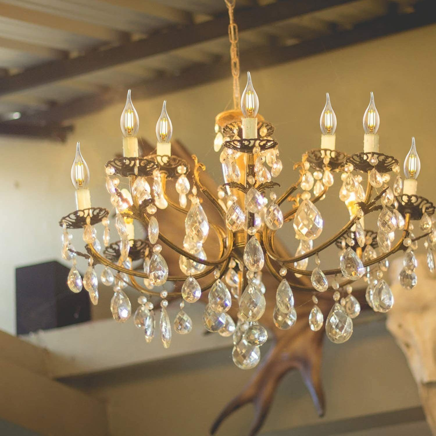 Un lampadario in ottone con gocce di cristallo e lampadine a candela pende dal soffitto.