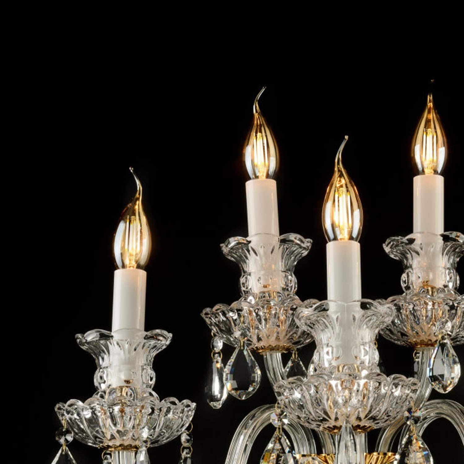 Un lampadario con quattro candele e gocce di cristallo su sfondo nero.