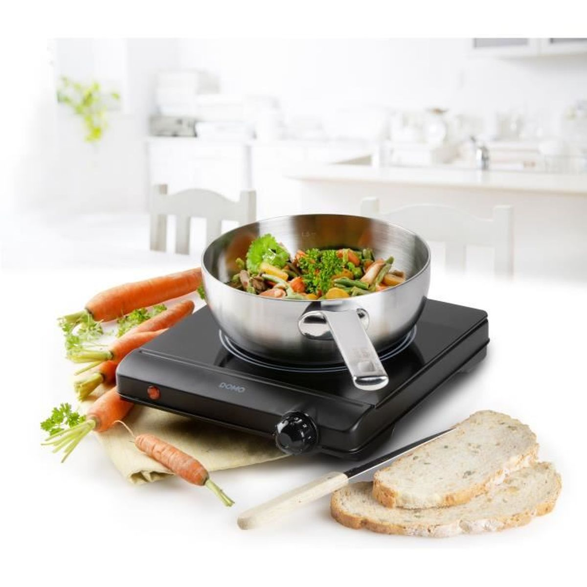 Une cocotte de légumes est posée sur une plaque chauffante noire, à côté de carottes et de pain.