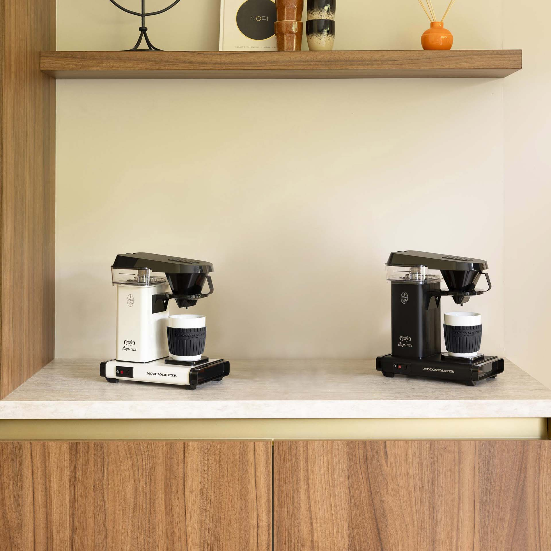 Zwei MoccaMaster Kaffeemaschinen, eine weiße und eine schwarze, stehen nebeneinander.