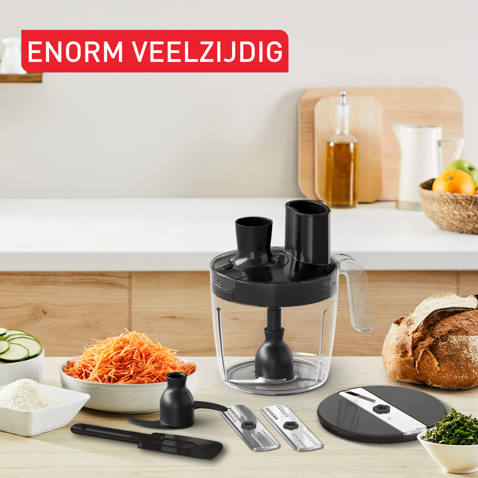 Keukenmachine met accessoires, messen, geraspte wortelen, courgette en brood.