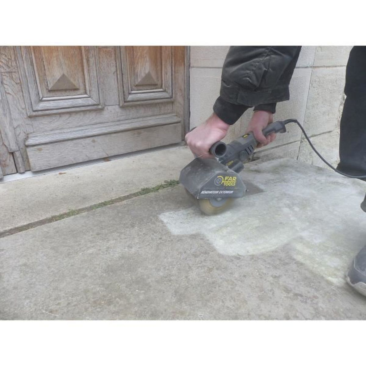 Man benutzt einen Schleifwerkzeug auf einem Betonboden vor einer Holztür.
