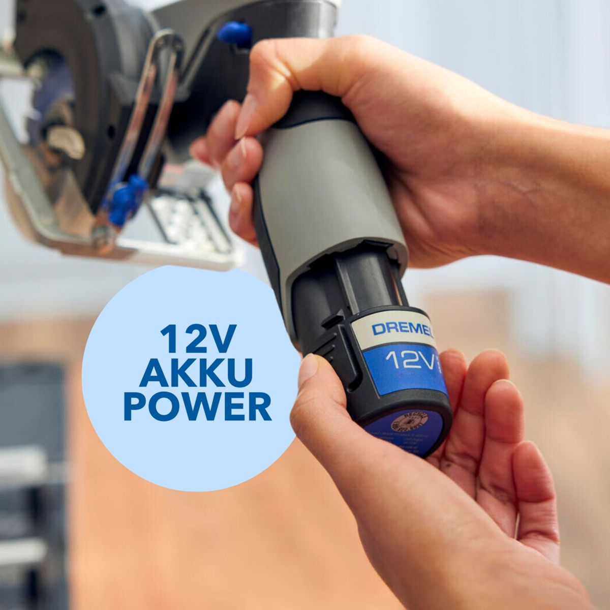 Hände stecken einen Dremel 12V Akku in eine Akkusäge. Text: 12V AKKU POWER.