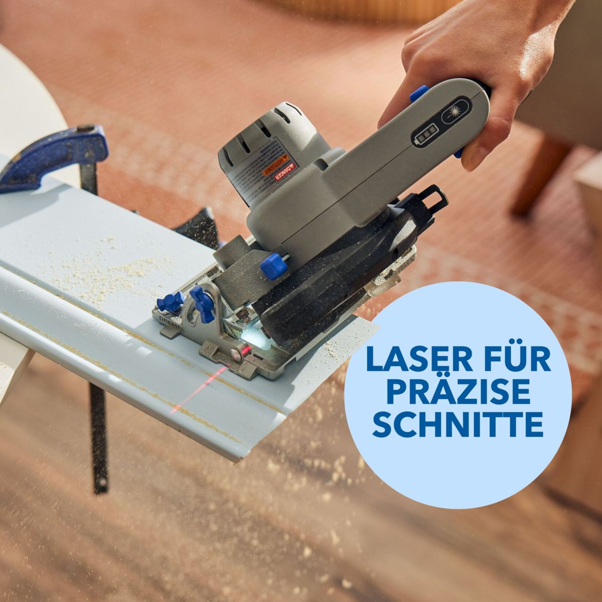 Kompaktkreissäge schneidet Holzleiste, Sägemehl fliegt, roter Laserstrahl.