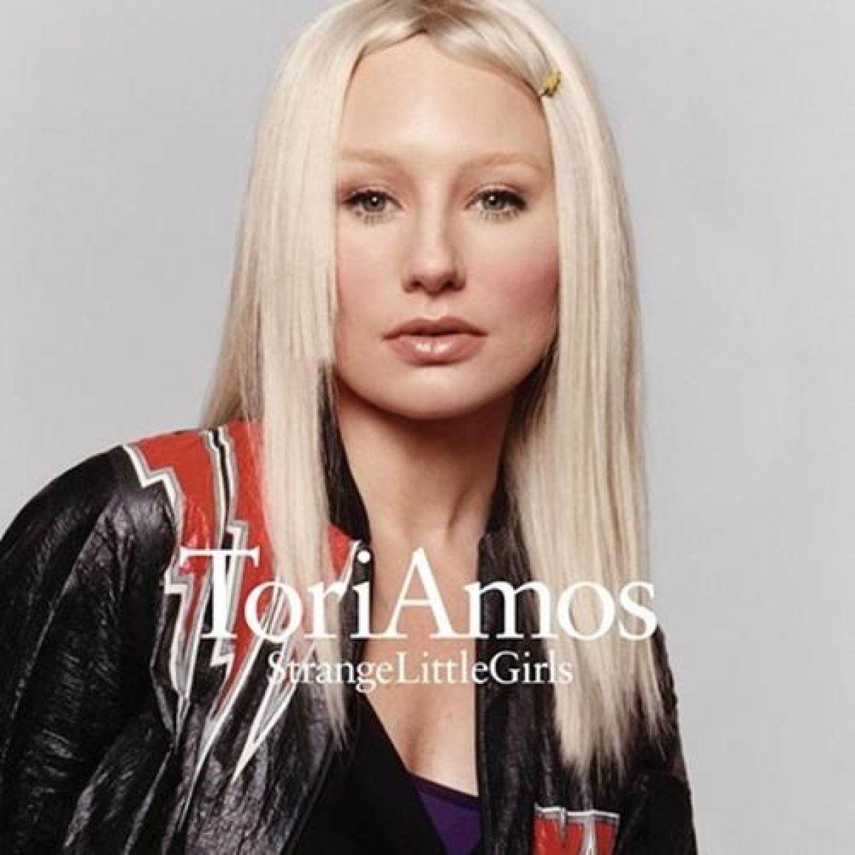 Tori Amos met blond haar draagt een leren jas met rode strepen.