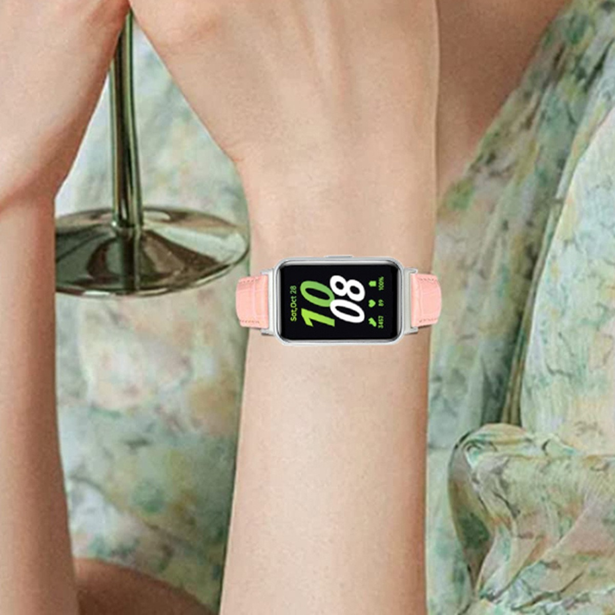 Eine Frau trägt eine Smartwatch mit rosa Armband am Handgelenk, die Uhrzeit ist 10:08.