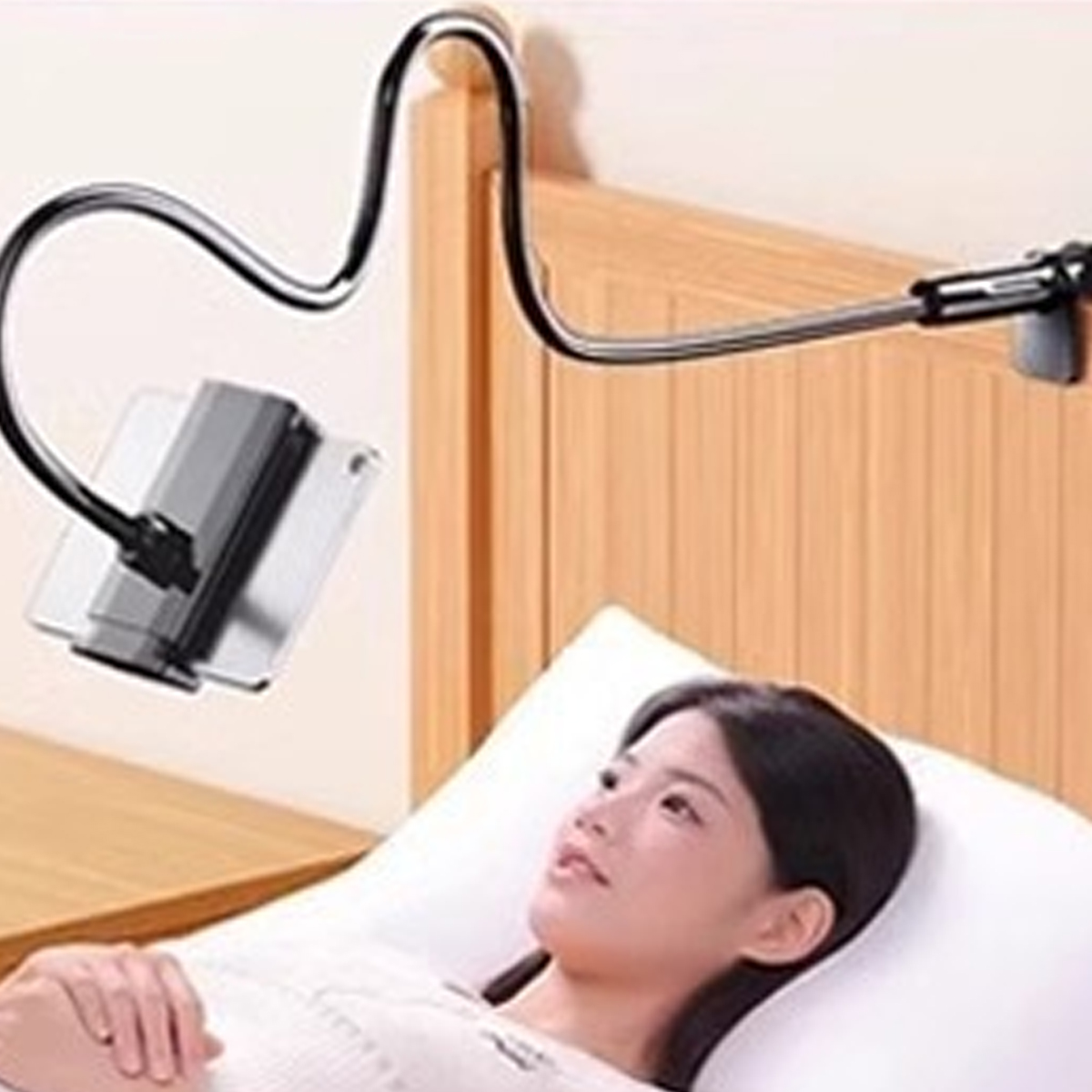 Eine Frau liegt im Bett, ein Handyhalter ist am Kopfteil befestigt.