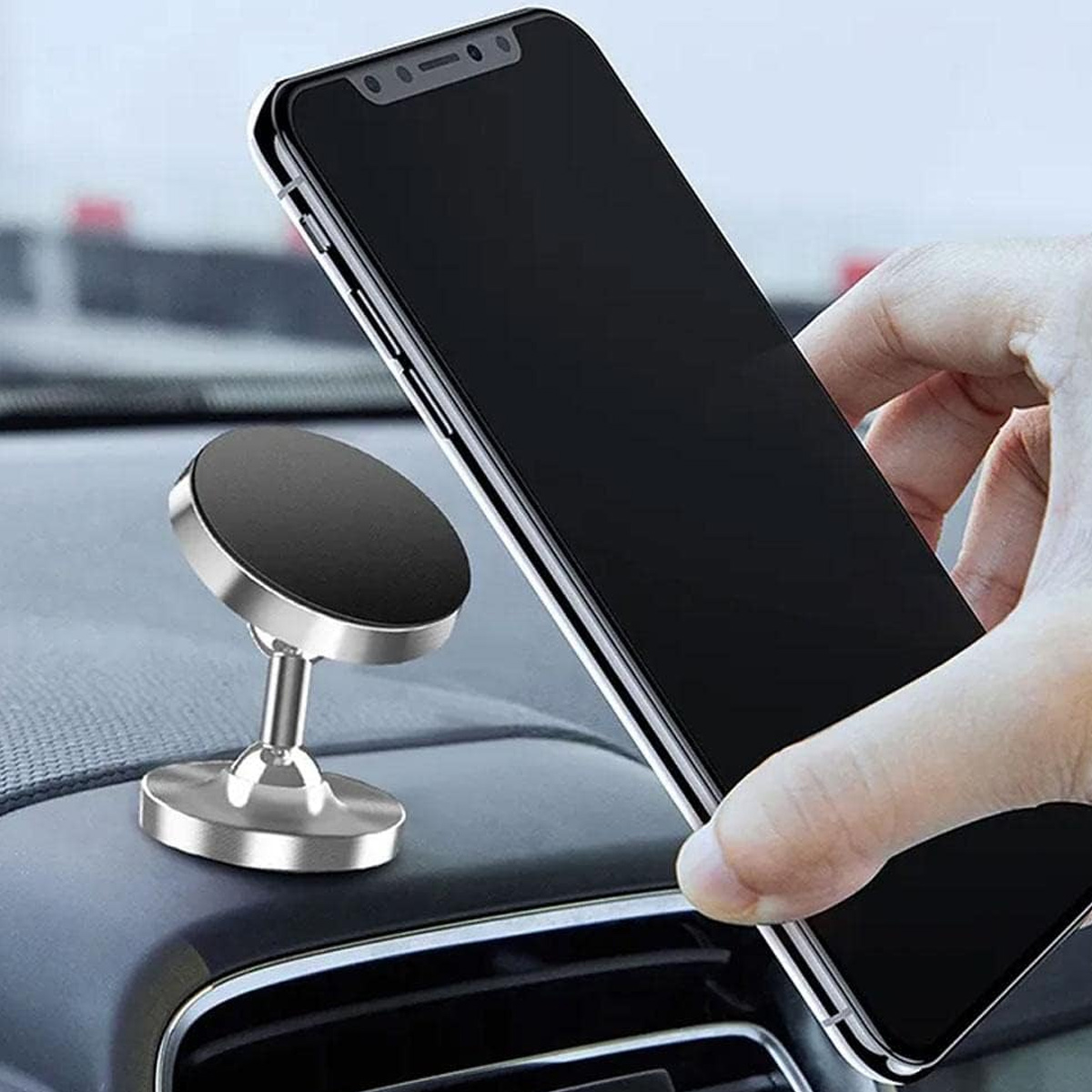 Eine Hand hält ein Smartphone über einem magnetischen Autohalter auf dem Armaturenbrett.