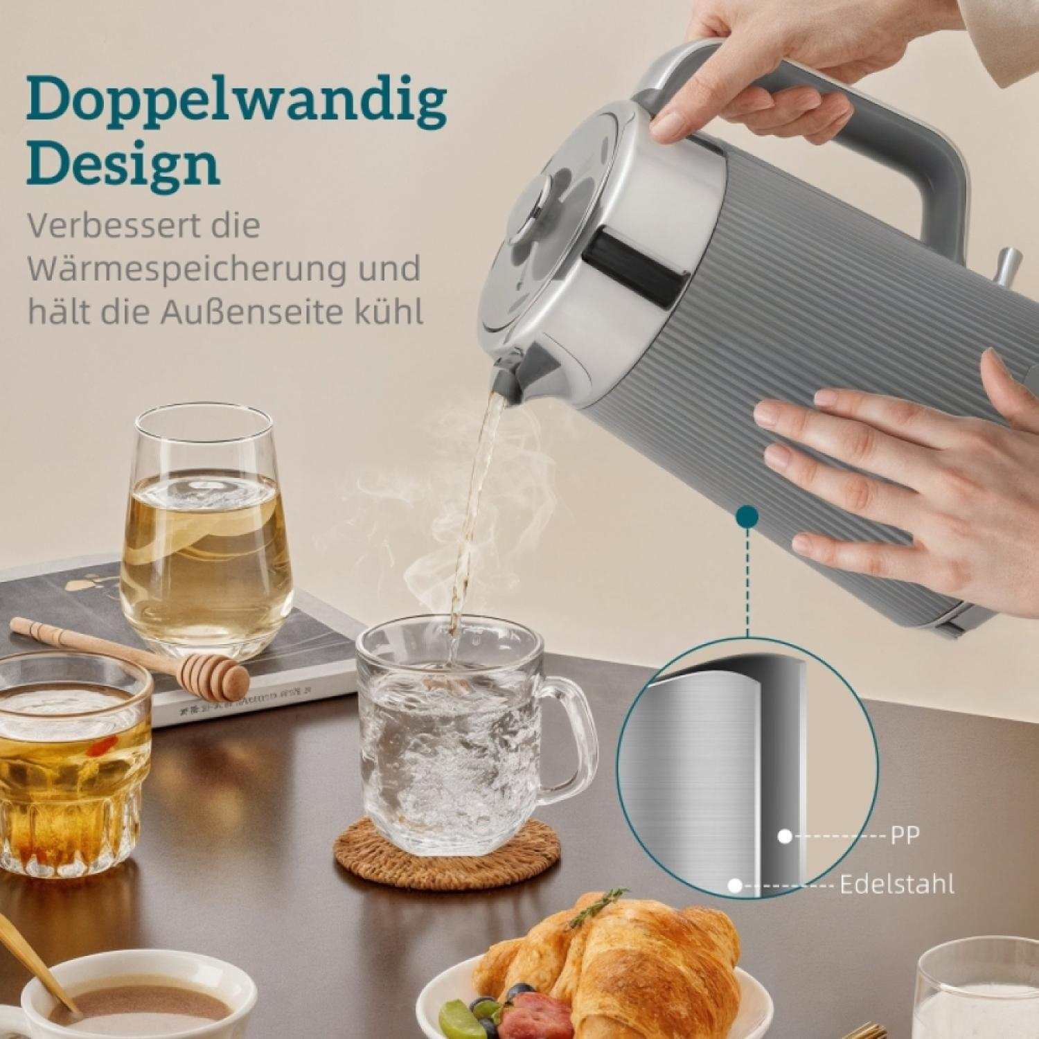 Grauer Wasserkocher gießt heißes Wasser in ein Glas, daneben Croissant und Tee.