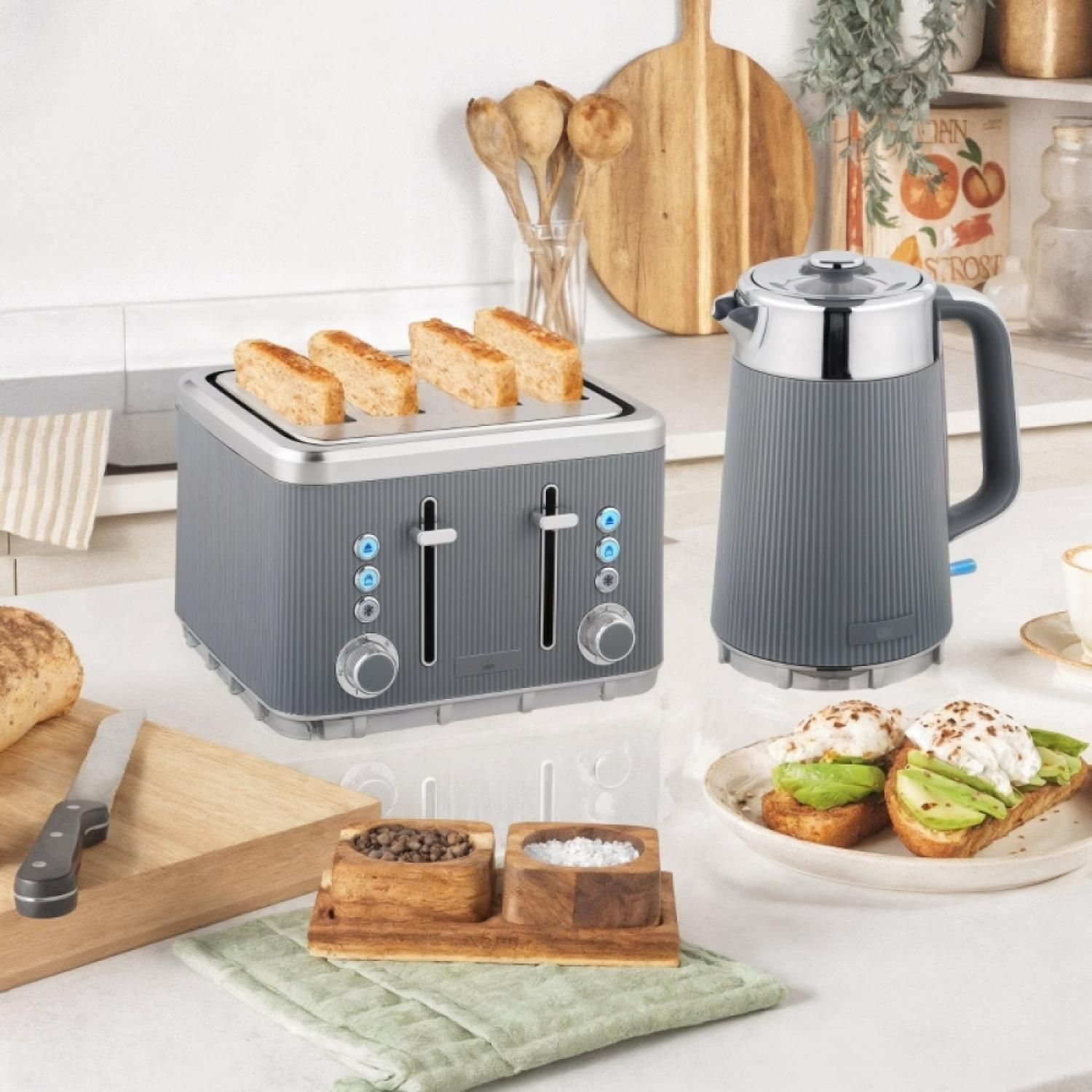 Grauer Toaster mit Toast, daneben eine graue Kanne, Avocado-Toast und Gewürze.