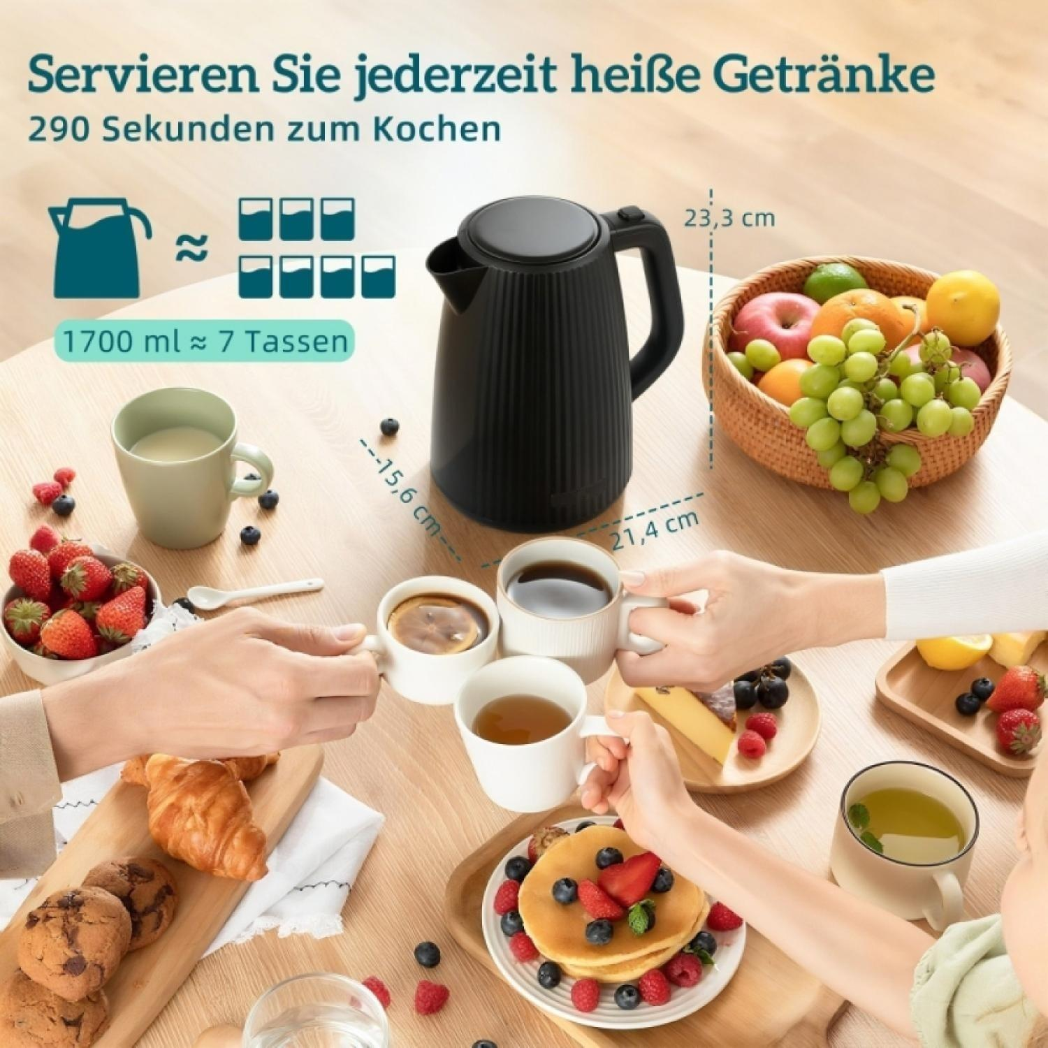 Schwarzer Wasserkocher mit Früchten und Frühstück auf einem Holztisch serviert.