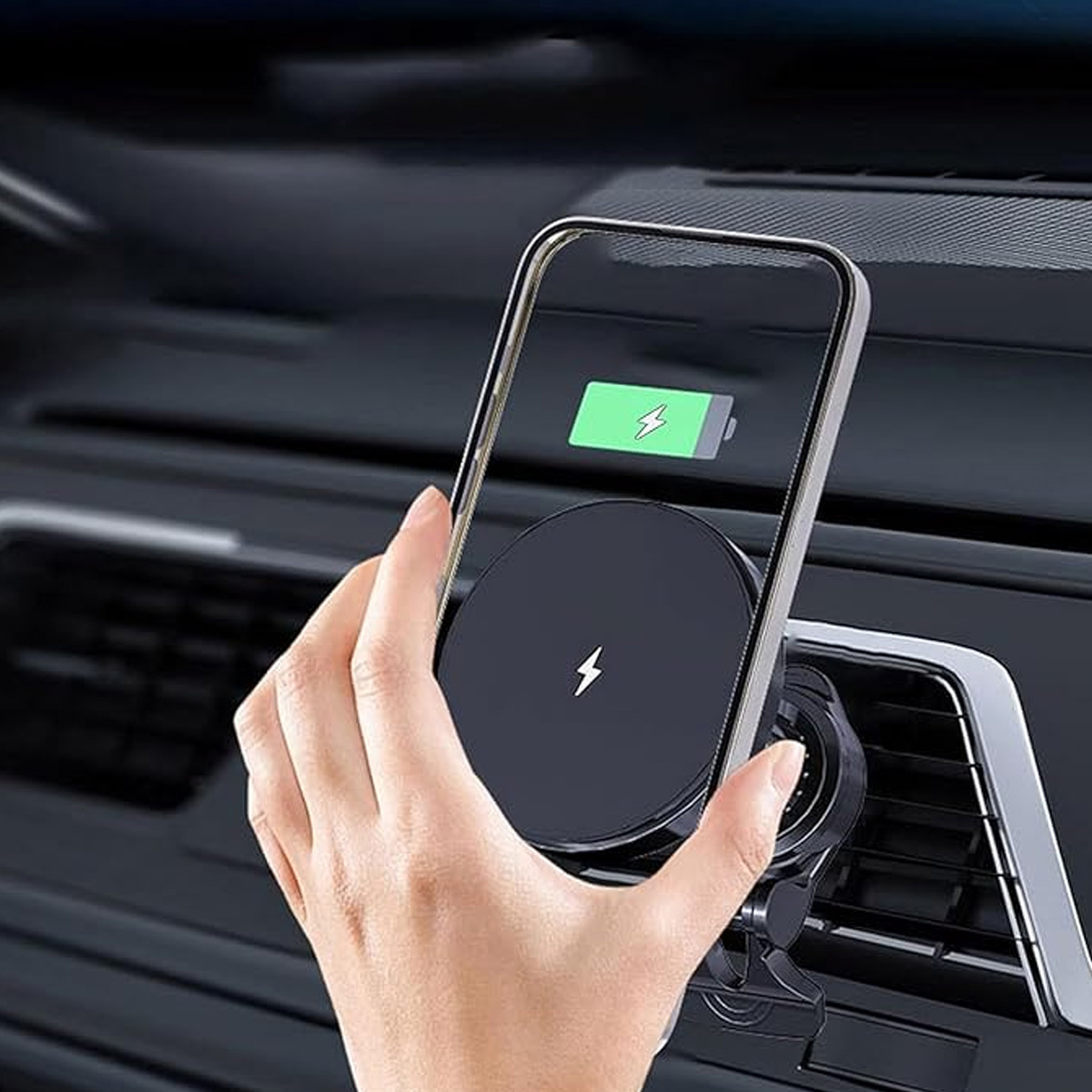 Hand hält Smartphone an Ladehalterung im Auto. Akku wird geladen.