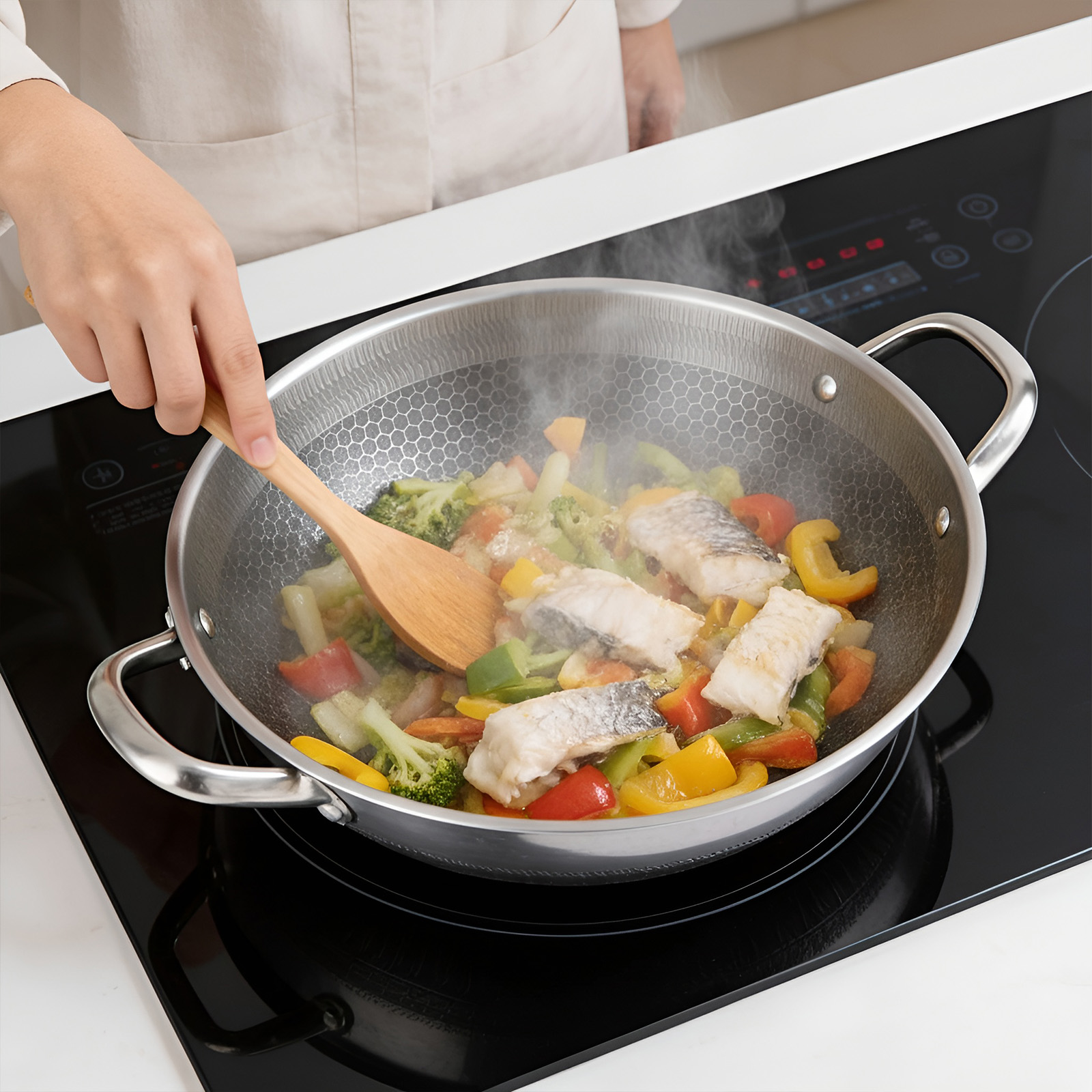 Du poisson et des légumes sont sautés dans un wok sur une plaque à induction.