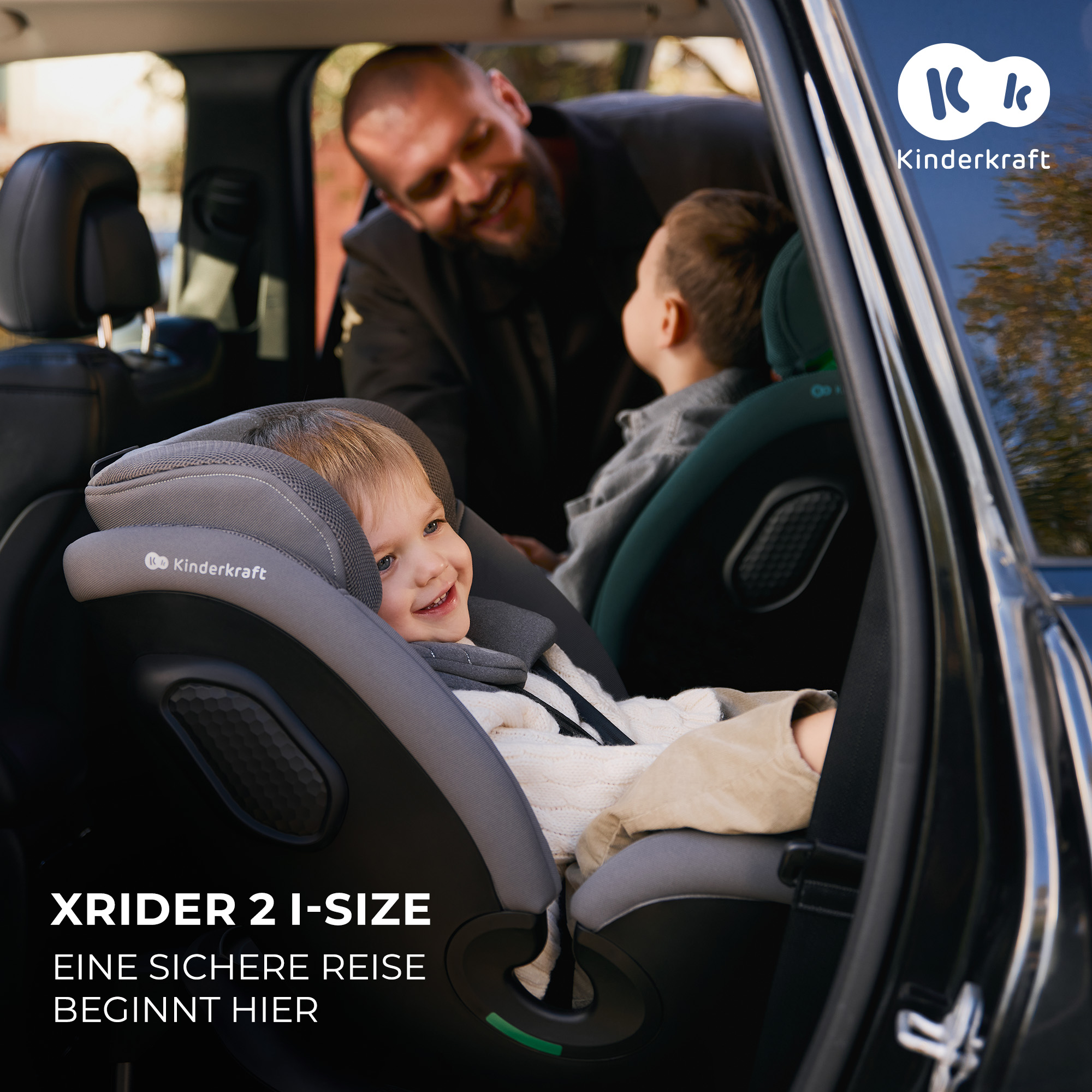 Ein Mann lächelt ein Kind in einem Kindersitz im Auto an.