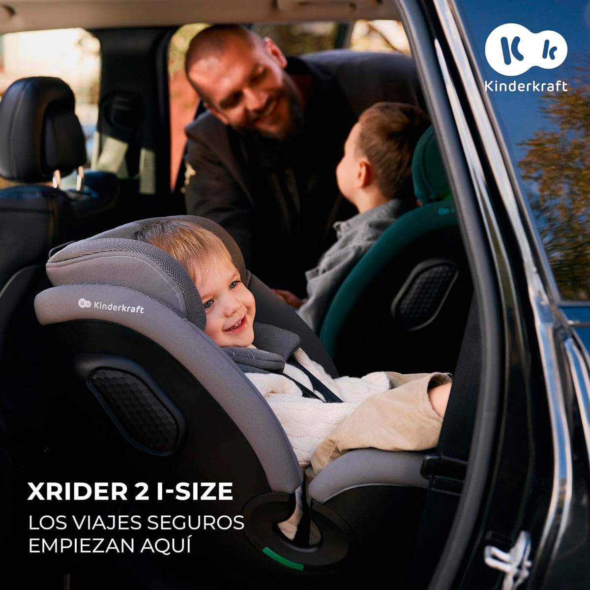 Ein Mann lächelt ein Kind im Kindersitz im Auto an.