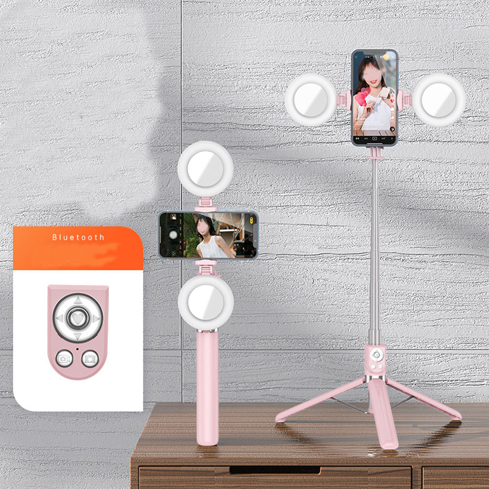 Ein rosa Selfie-Stick mit Ringen und Telefonen auf einem Holztisch.