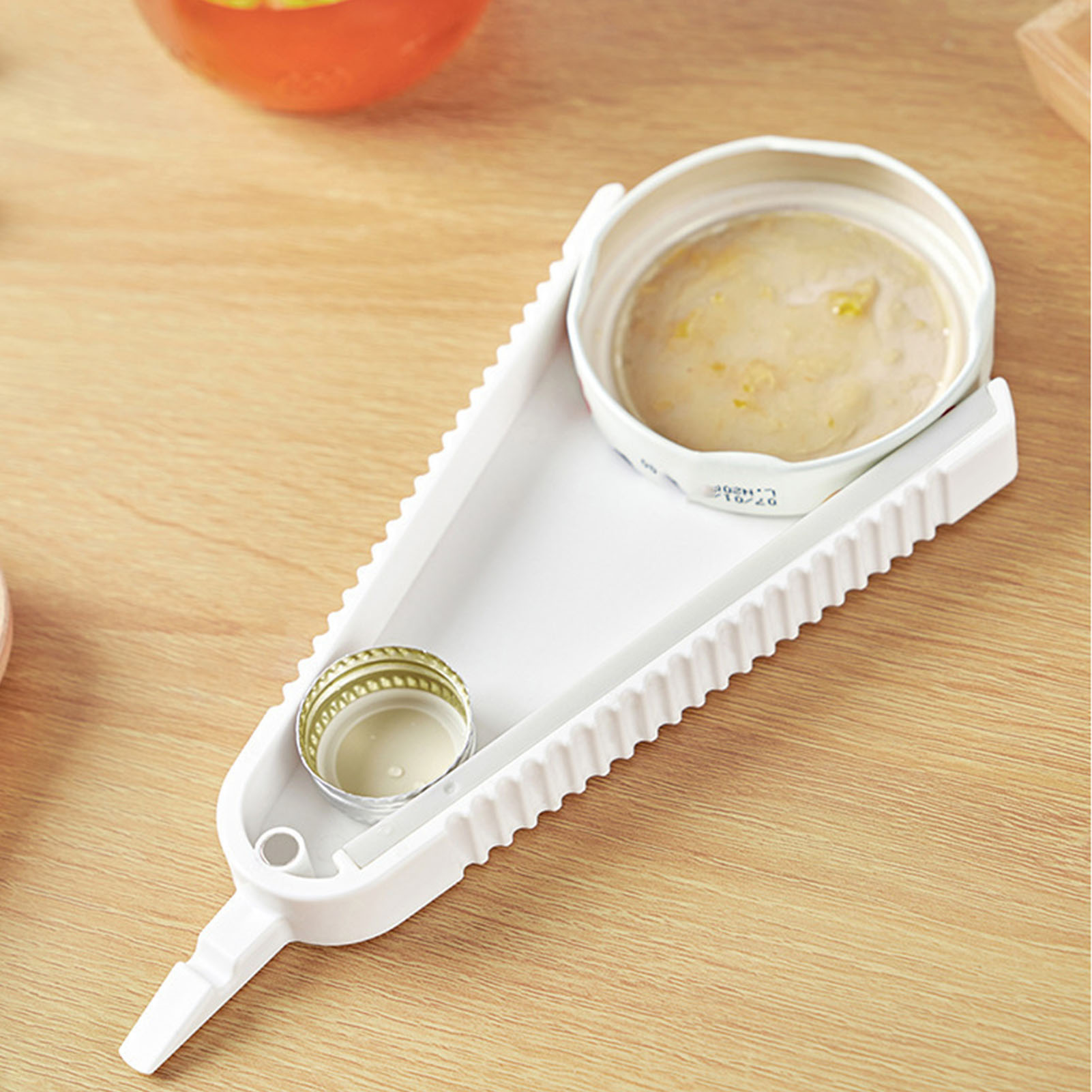 Ein weißer Dosenöffner mit einem Kronkorken und einer geöffneten Dose gefüllt mit Essen.